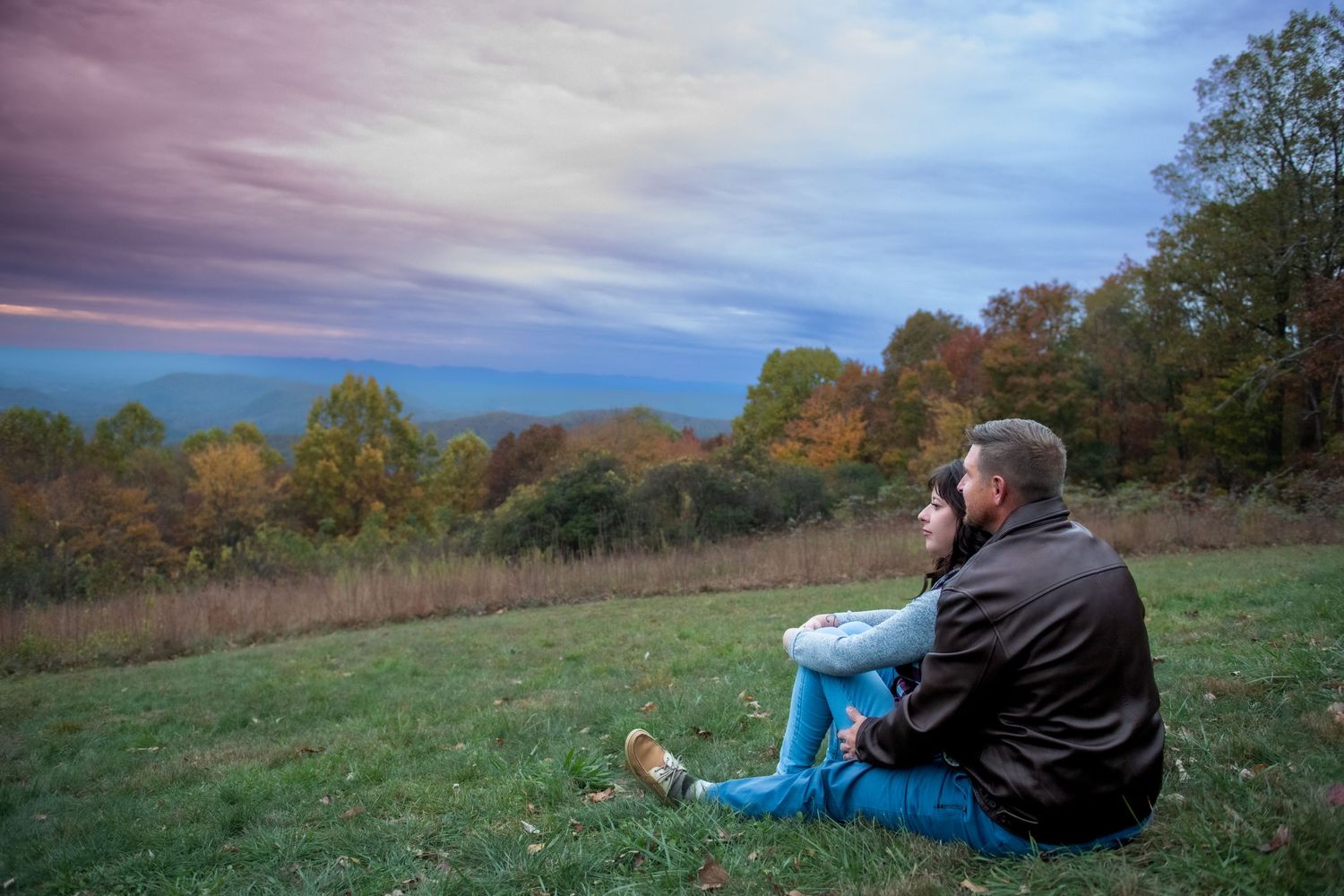 A series of panoramic photos showing a couple sitting on a grassy hilltop during sunset with autumn trees in the background.