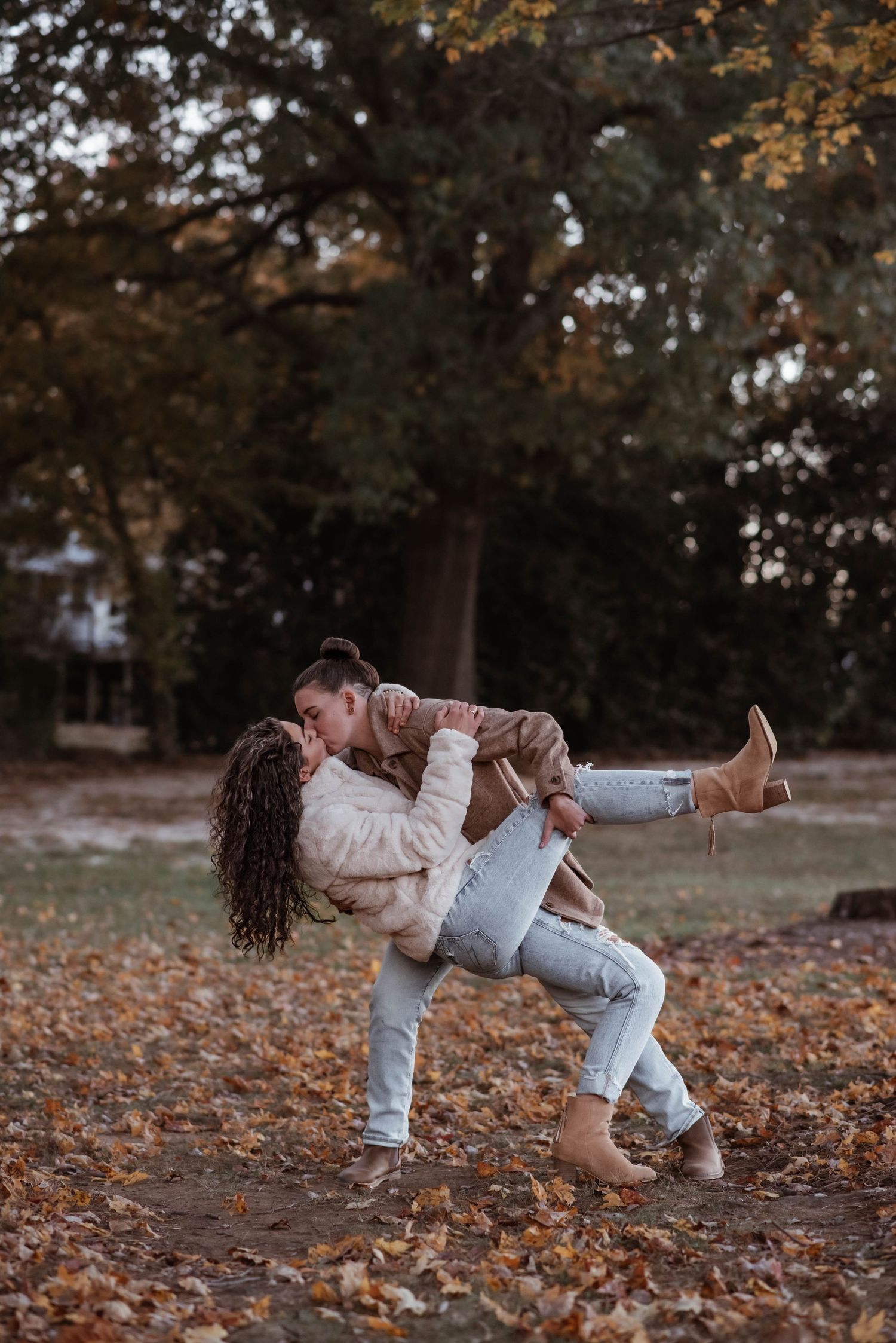 Playful autumn photoshoot with falling poses among scattered orange leaves.