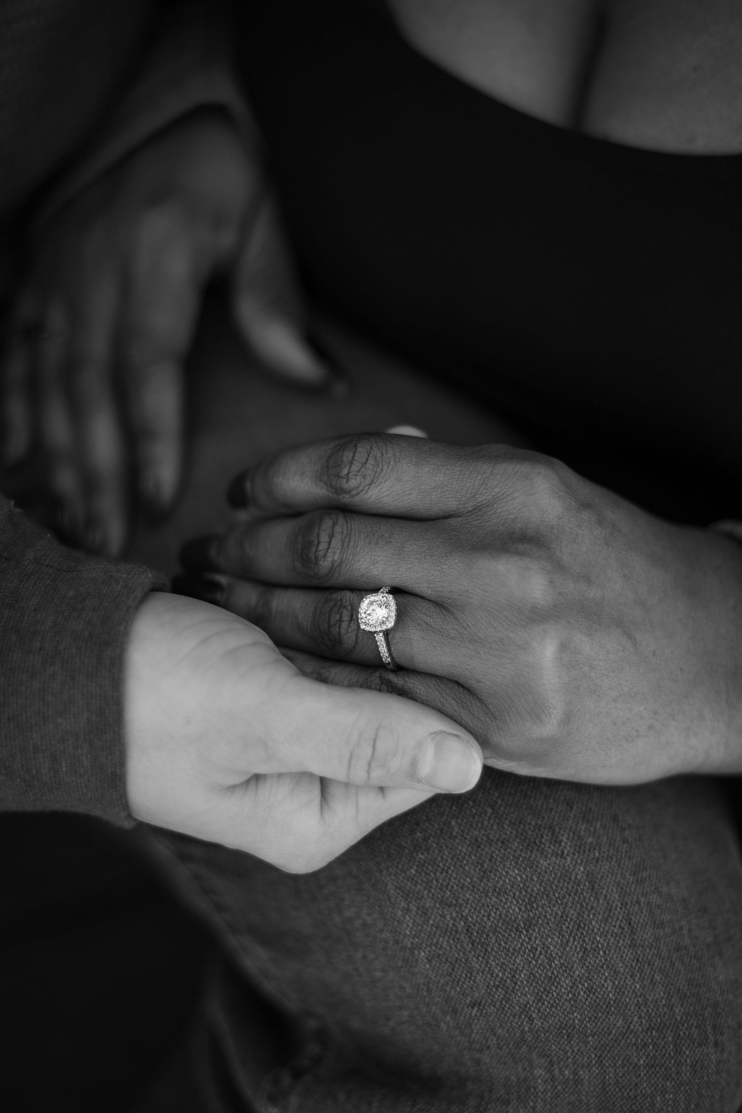 Close-up black and white shots of hands with an engagement ring.