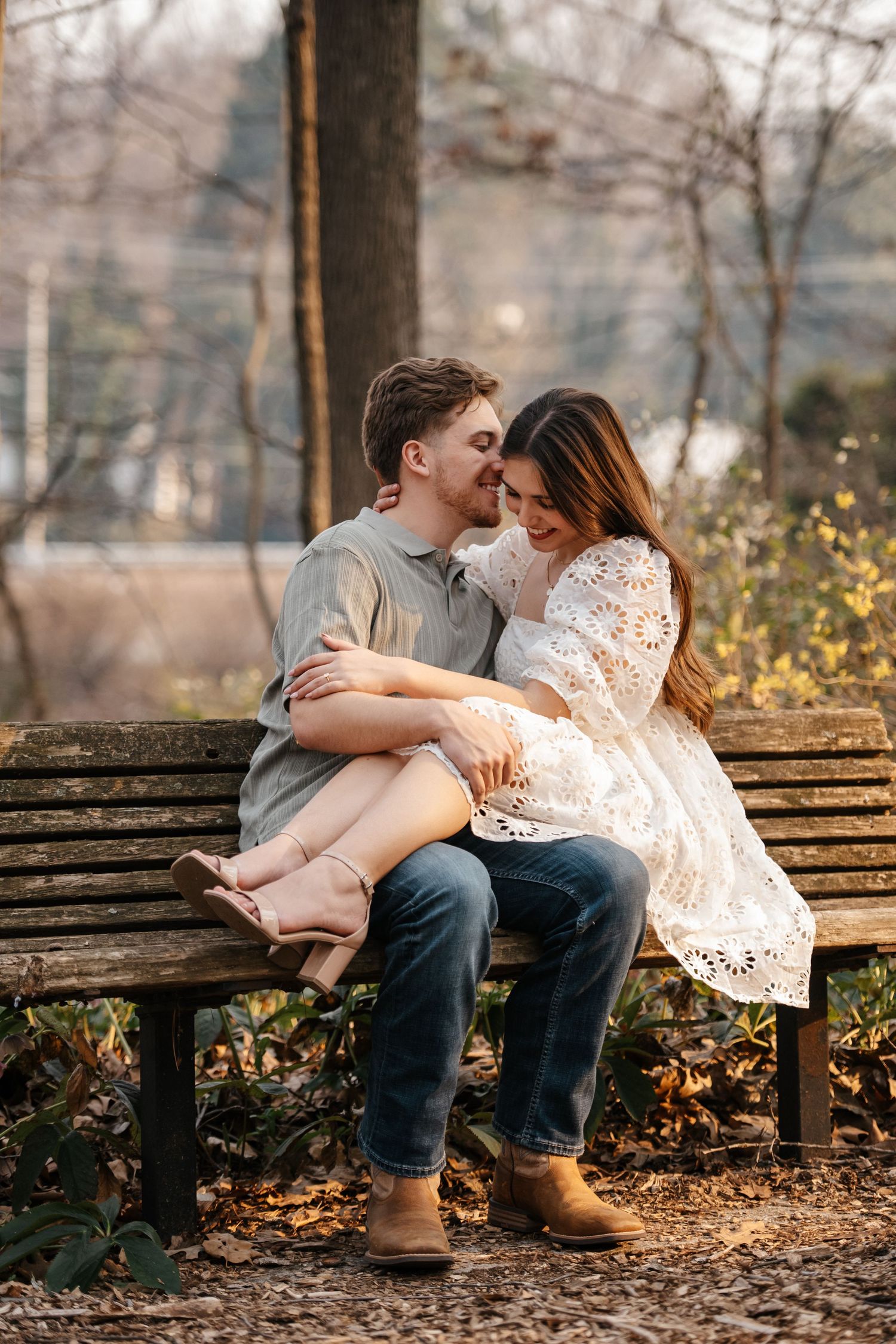 Romantic couple sharing intimate moments on a wooden bench surrounded by autumn foliage.