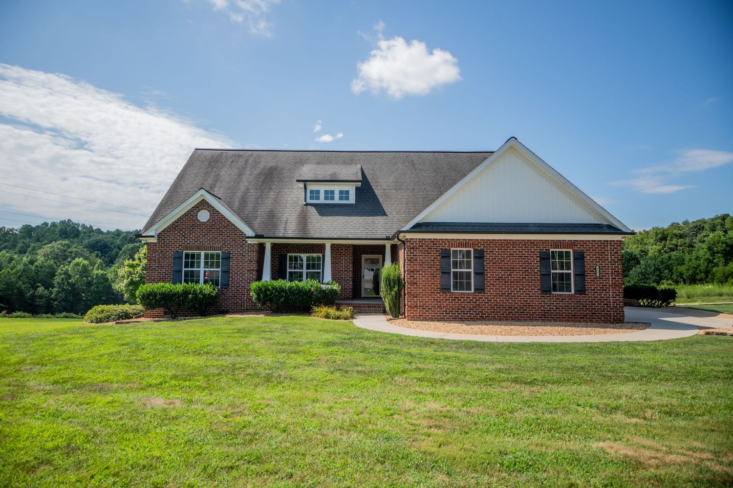 Row of brick ranch homes with manicured lawns on a gently sloping hillside.