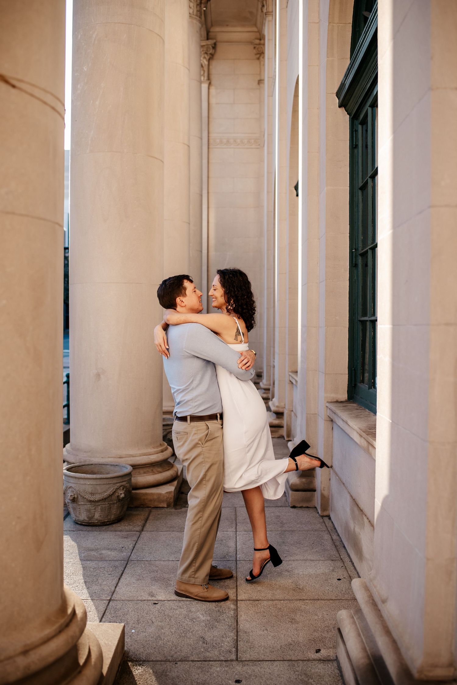 A romantic embrace between columns of a classical building.