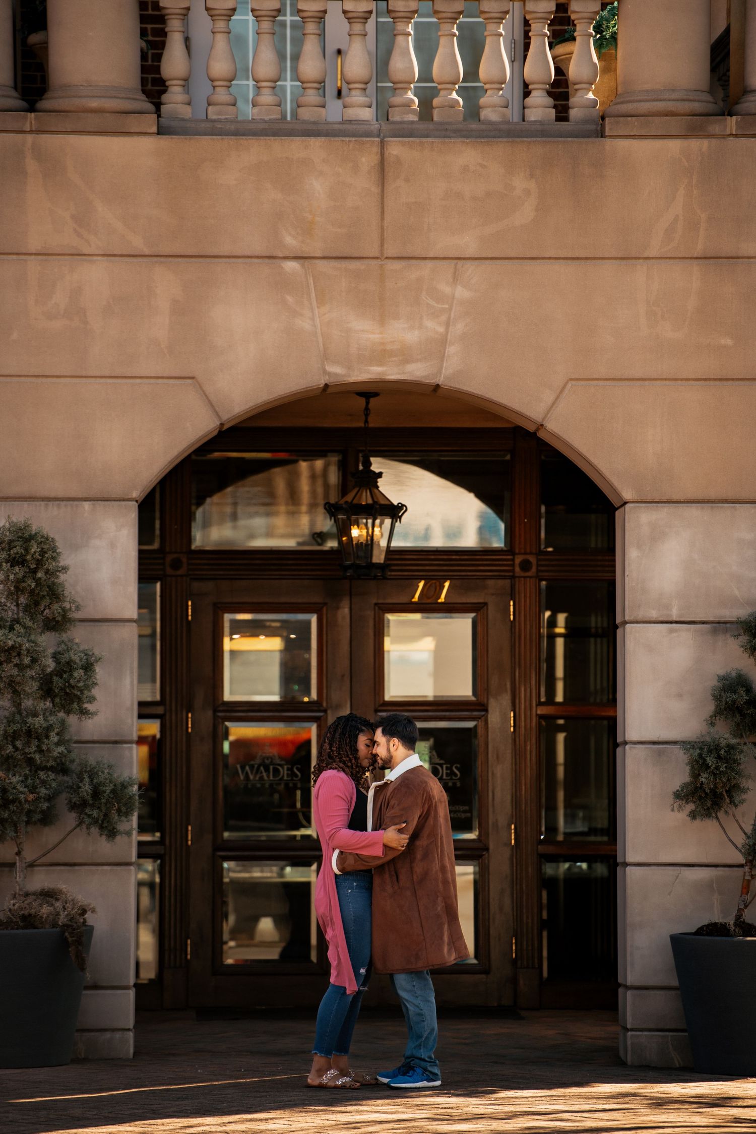 Couple sharing tender moments outside an elegant building with classical architecture.