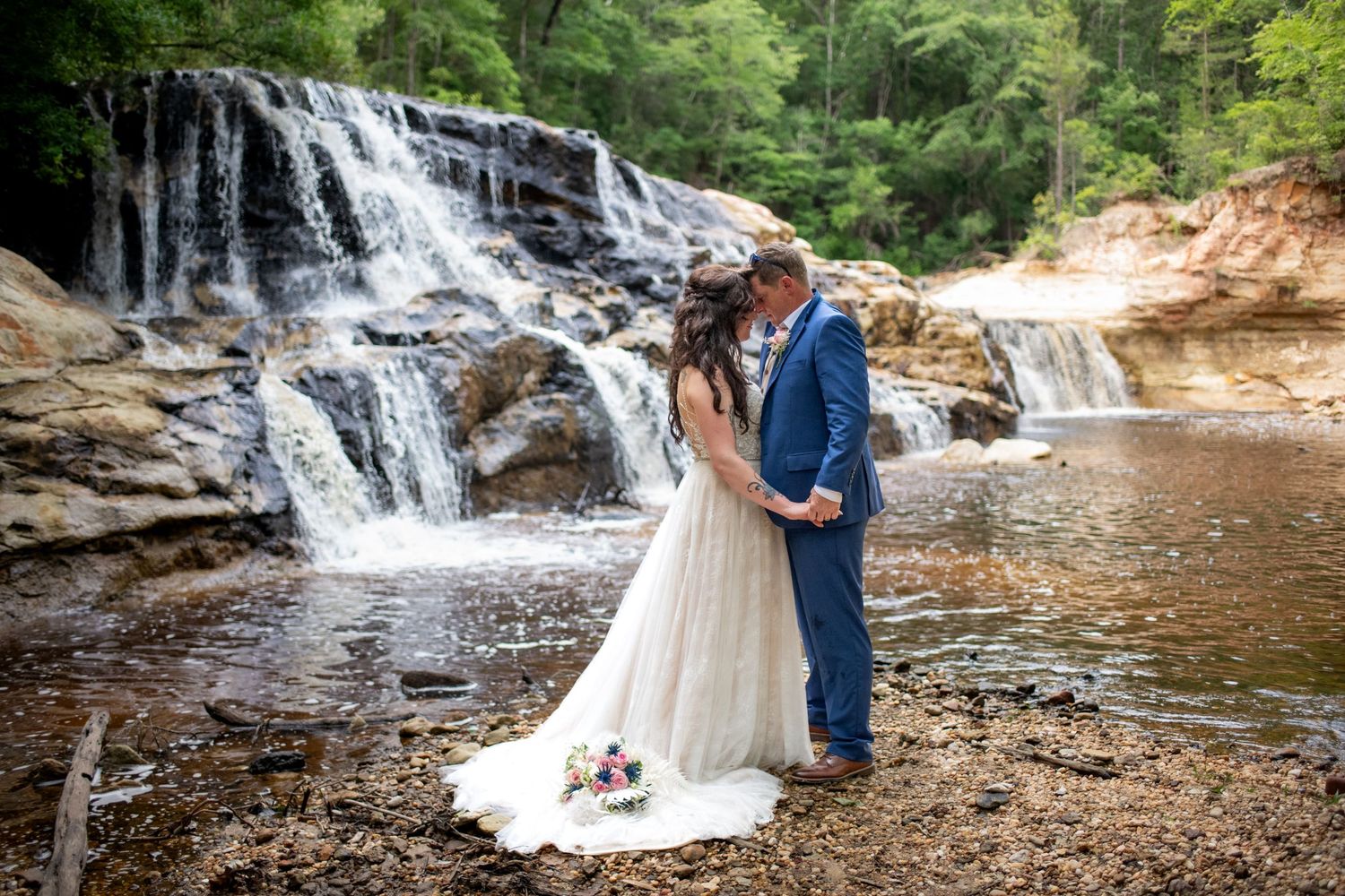 A romantic waterfall wedding photo with cascading water in the background.