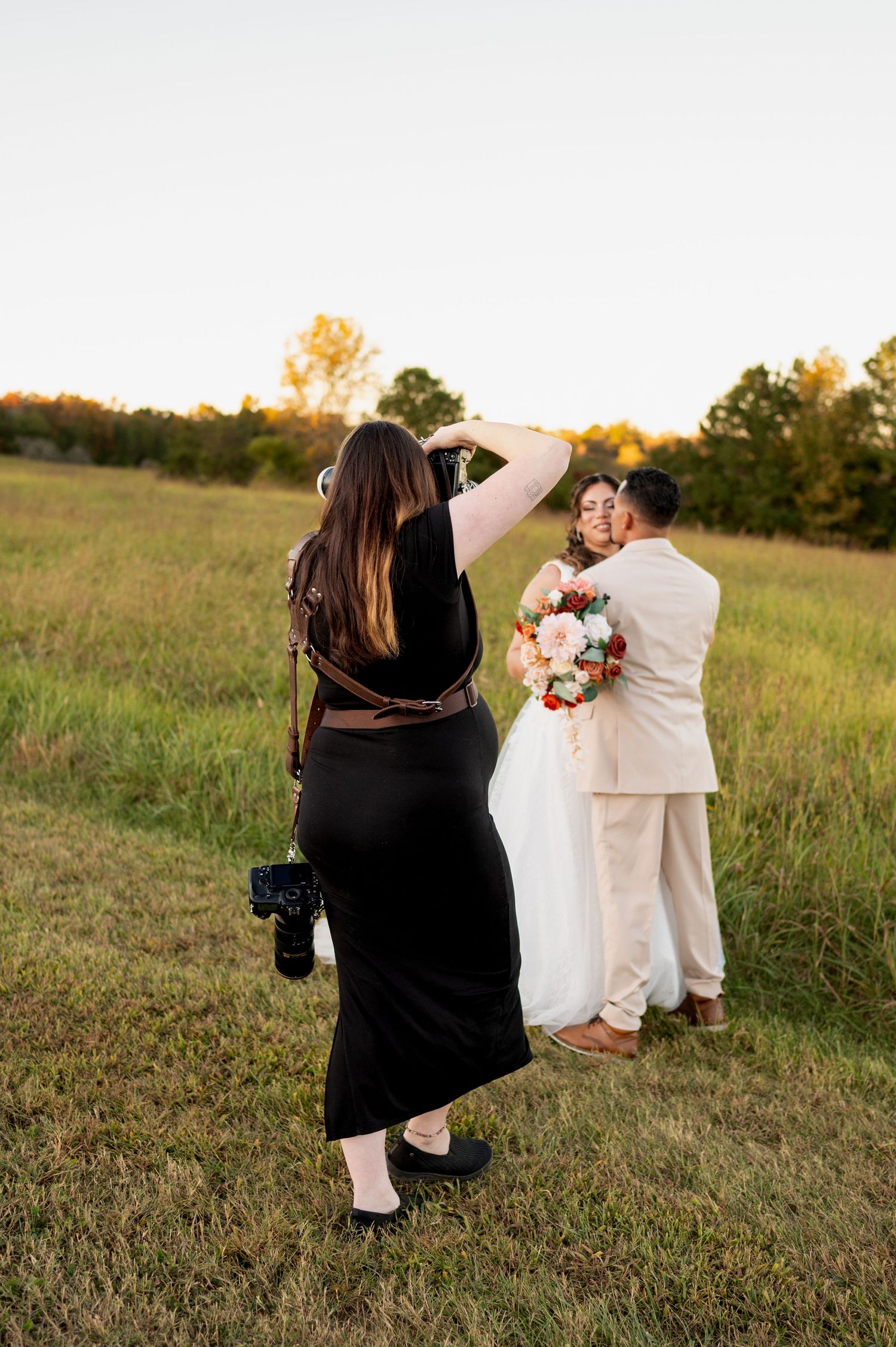 Wedding photographer captures couple in golden field during sunset photo session.