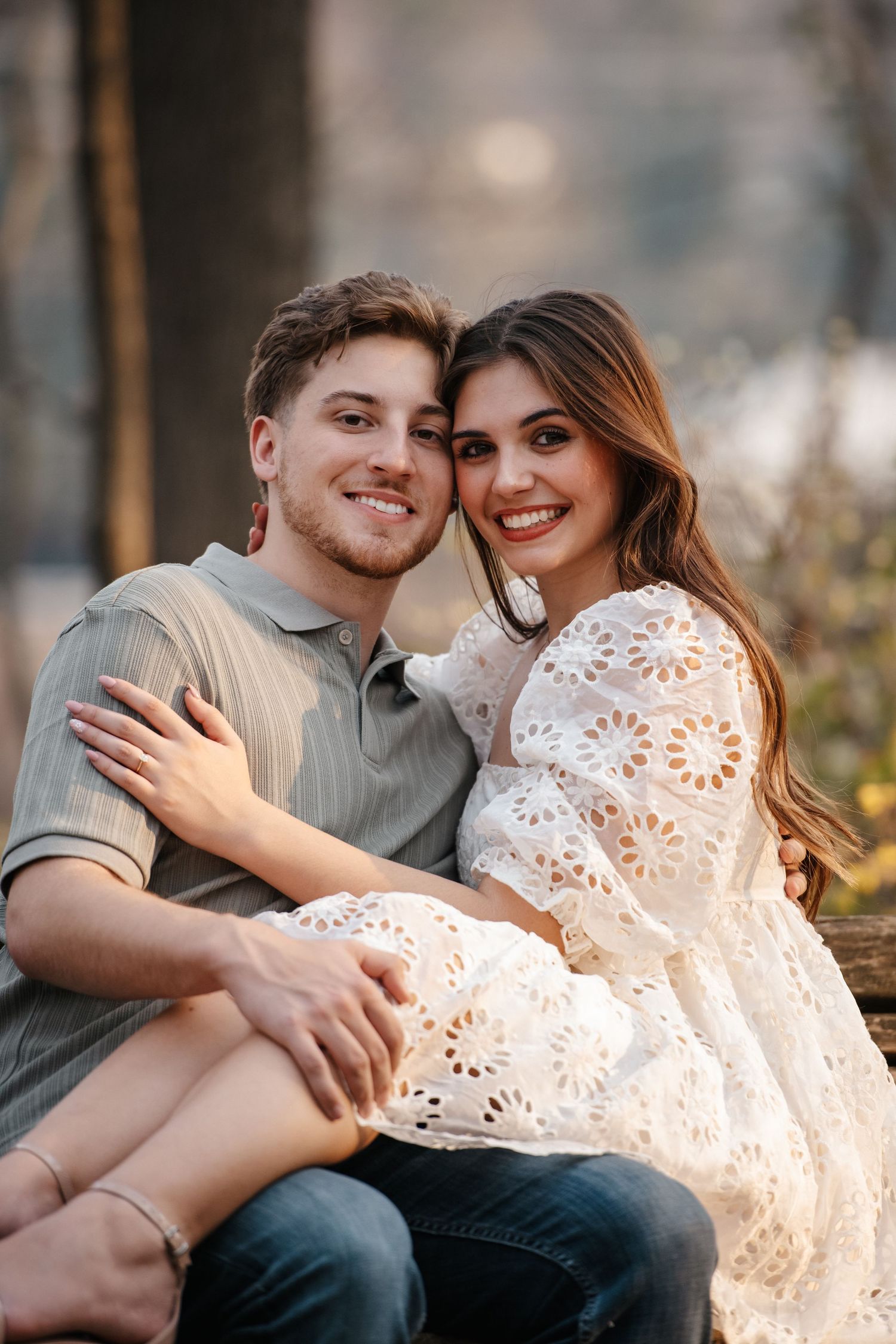 Sweet candid moments between a couple sitting together on a bench in a park setting.