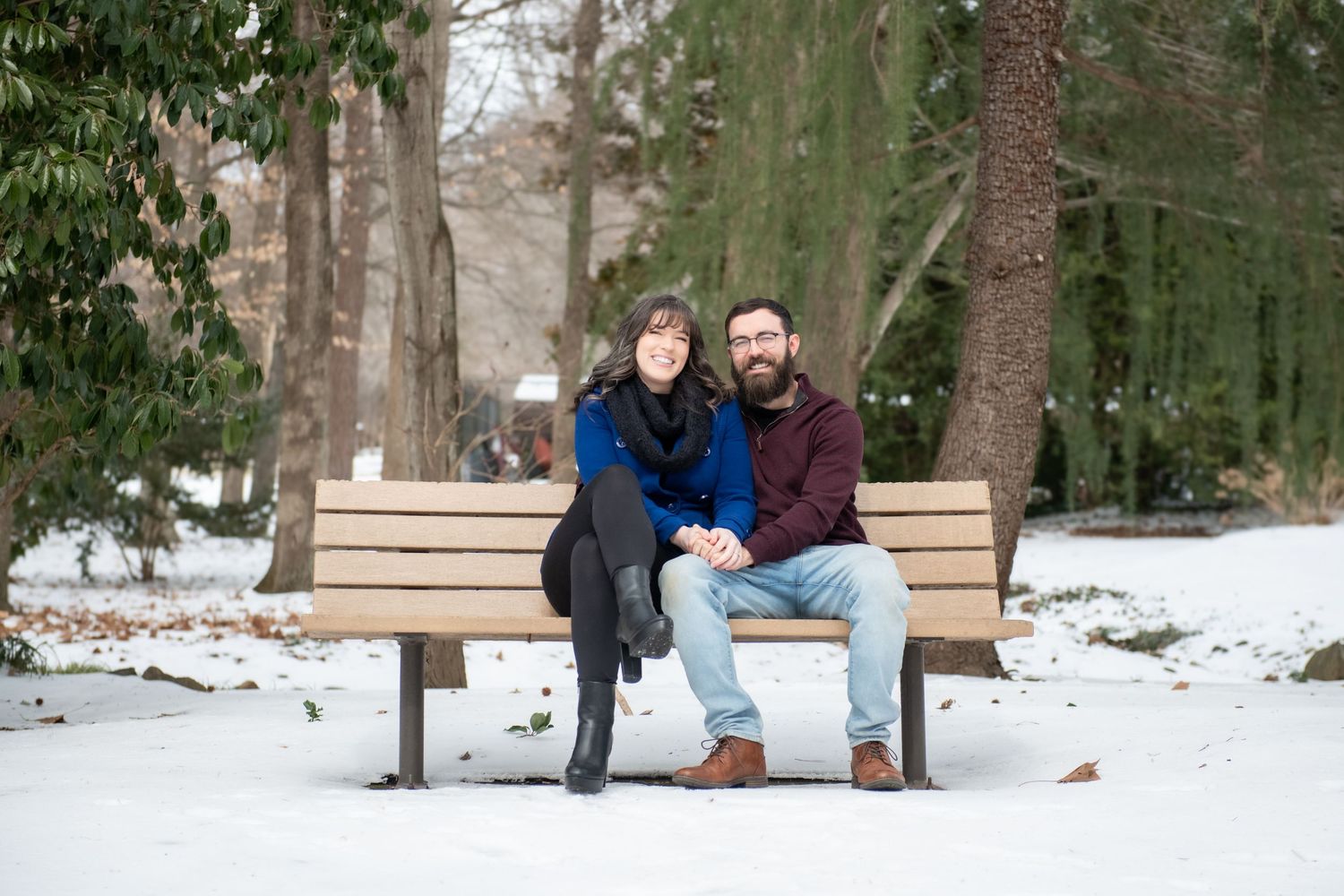 A group enjoys a winter day on a snowy hill in a wooded park setting.
