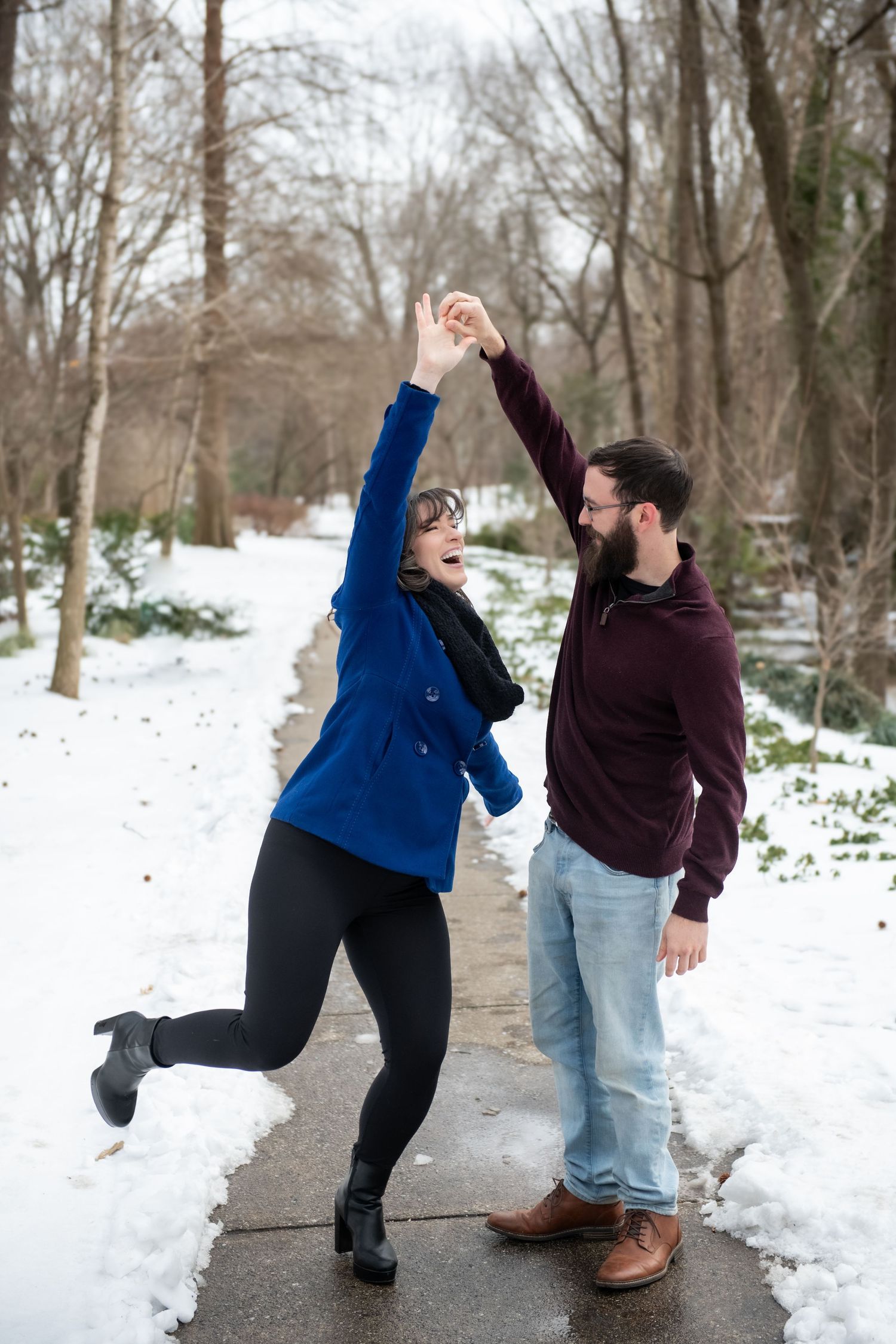 A couple dances and plays in the snow during their winter photo session.