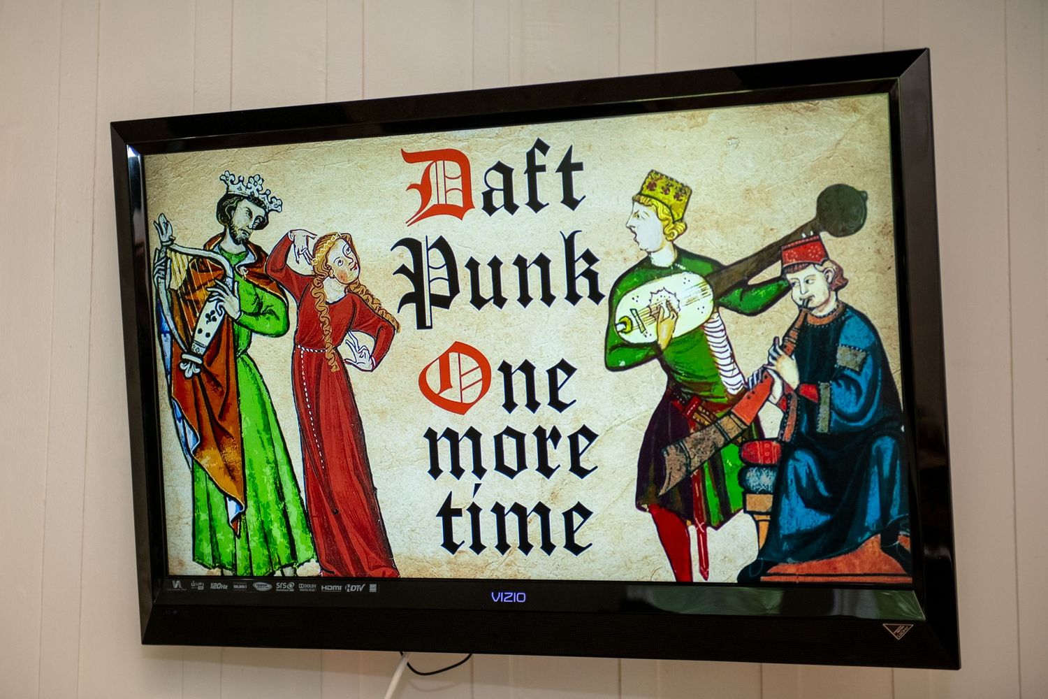 A Vizio TV displaying medieval-style artwork with Daft Punk One More Time text on a white wall.