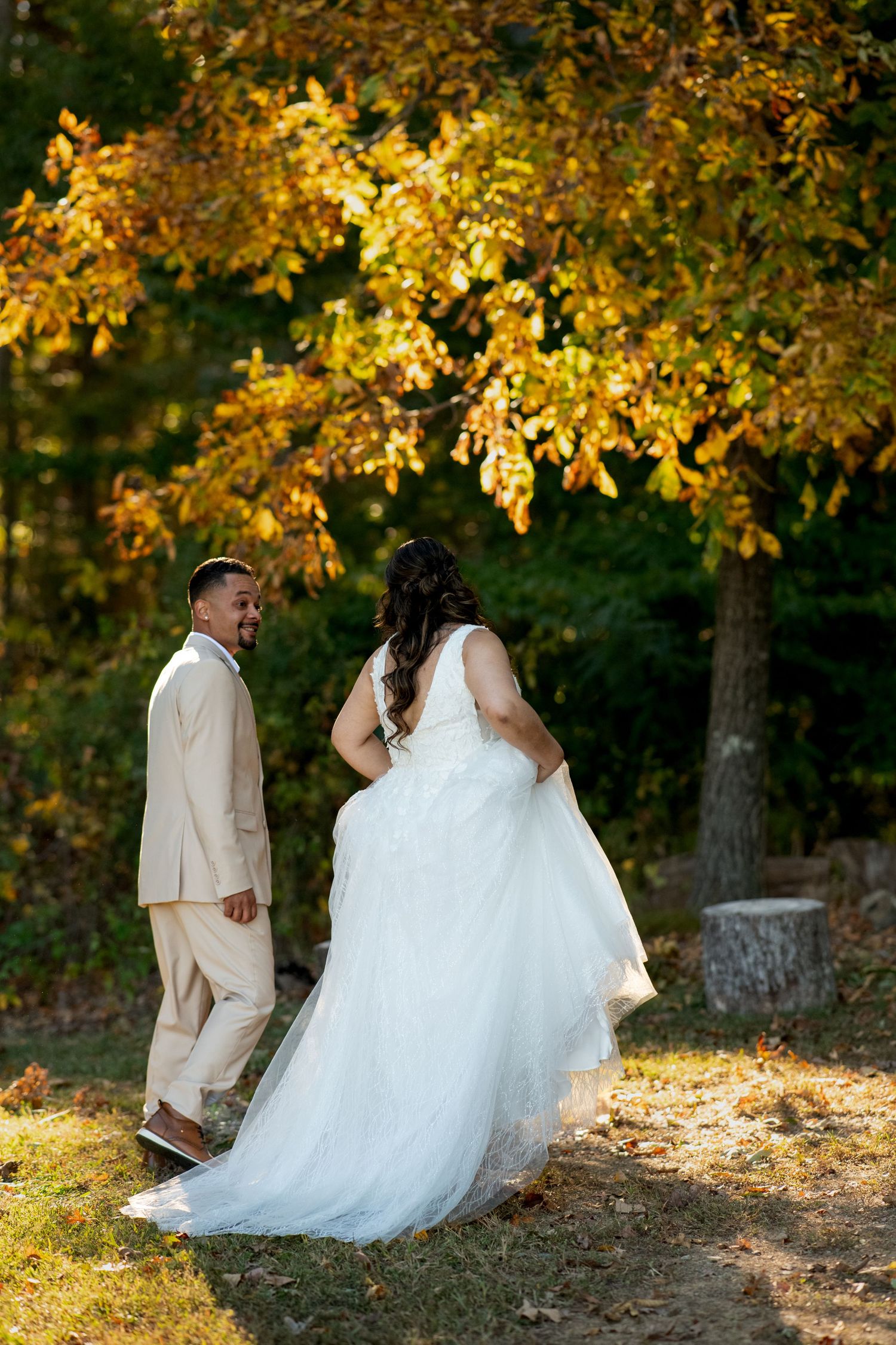 Romantic autumn wedding photos captured in a wooded area with golden leaves and natural sunlight.
