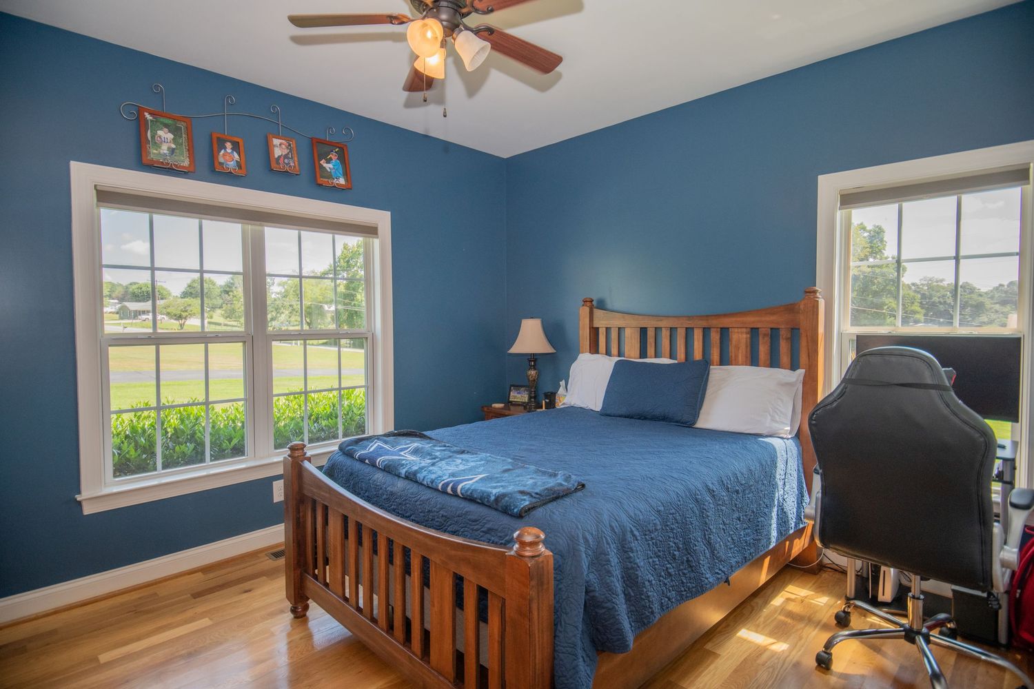 Spacious bedroom with blue walls, wooden bed frame, and ceiling fan.