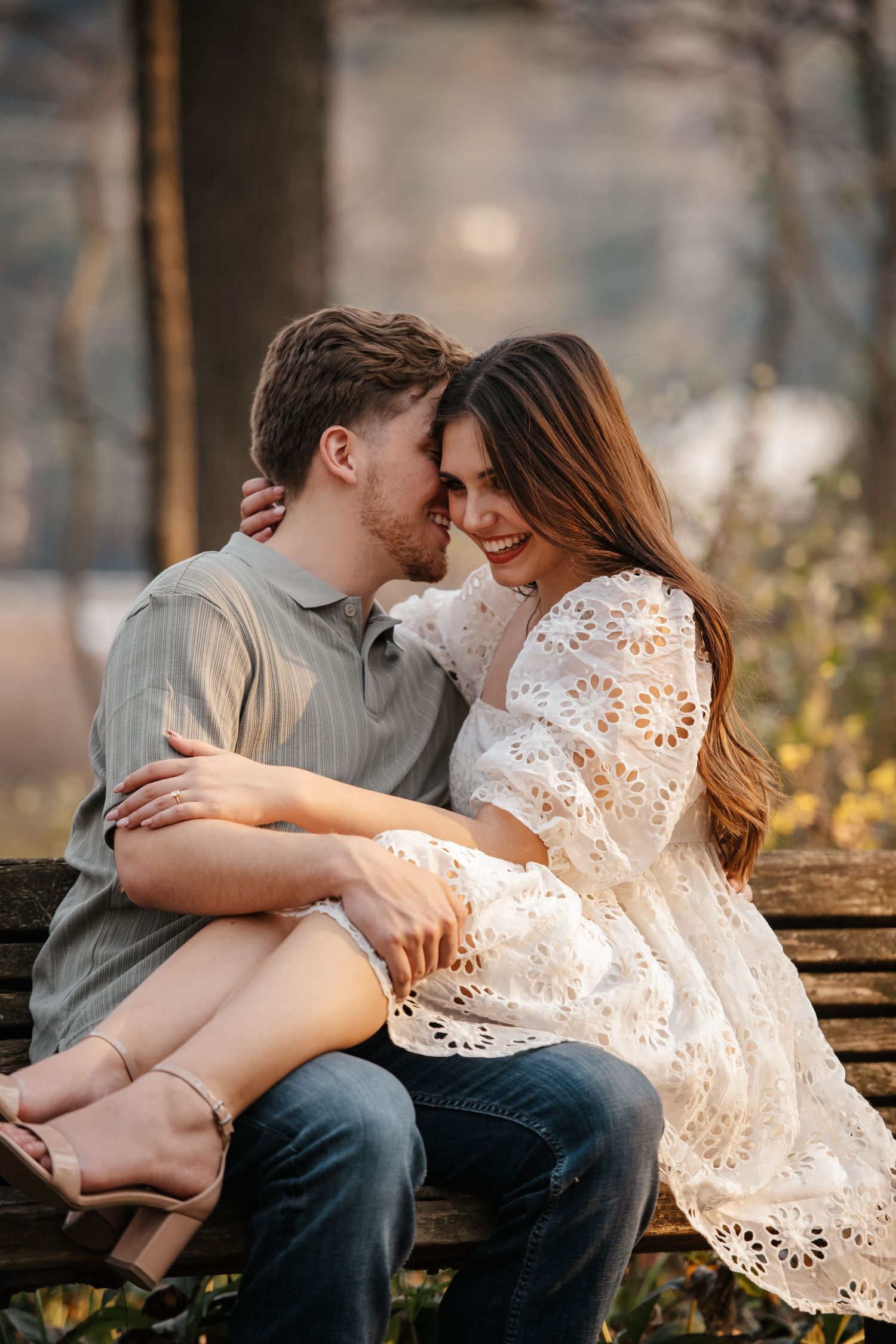 Couple in casual attire embracing tenderly on a park bench during golden hour.