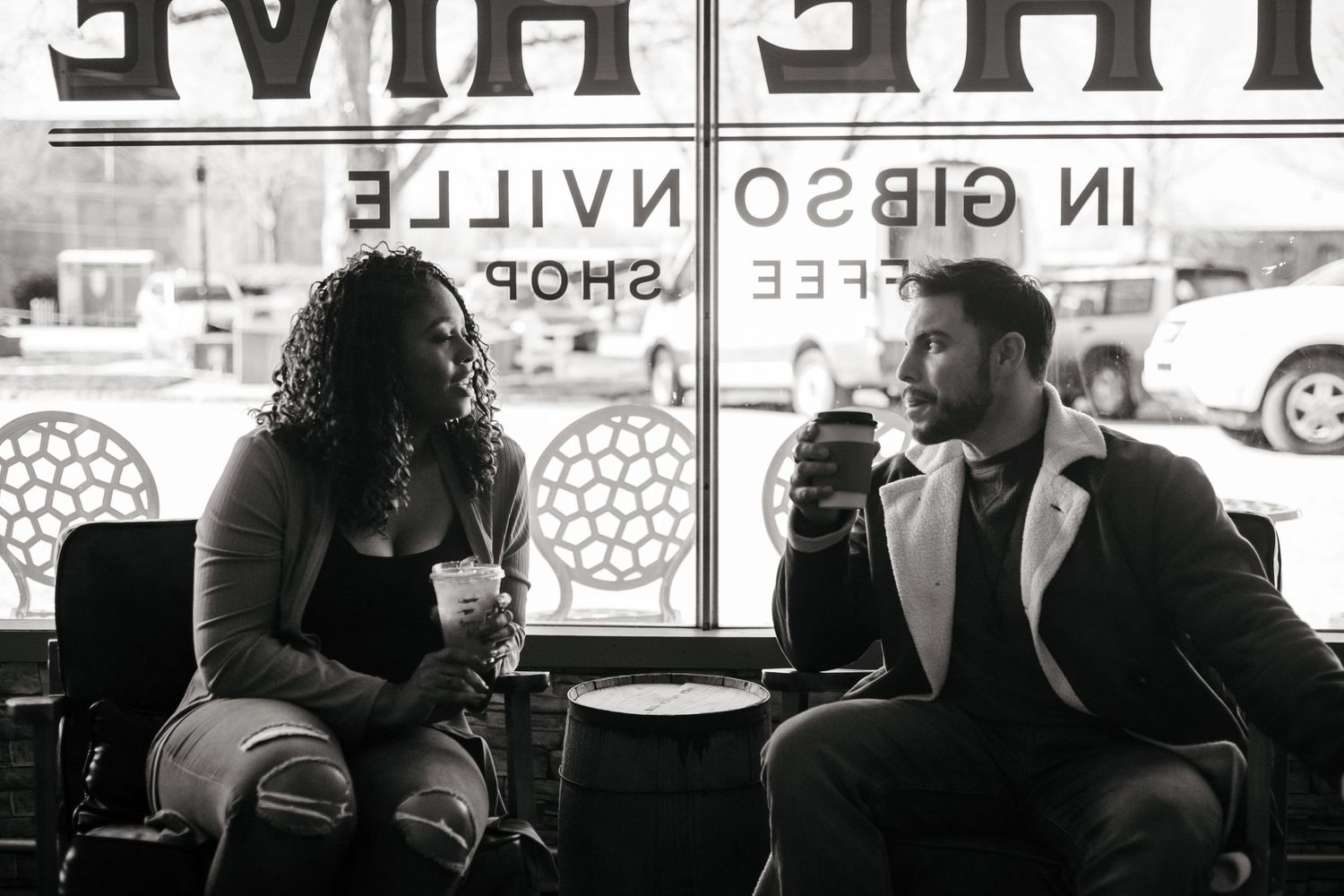 Couple sitting together in a cafe with reversed text visible in the background.