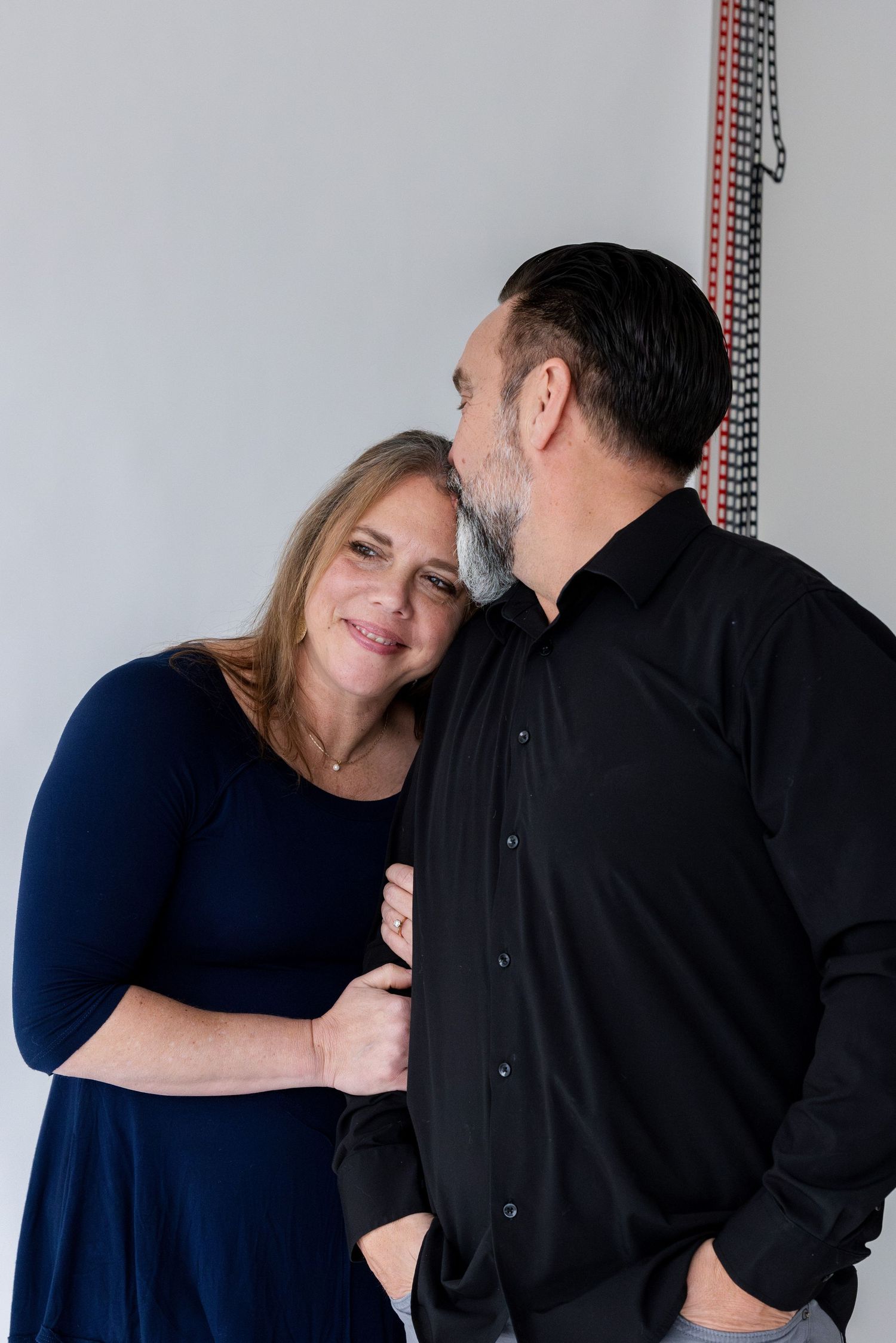 A couple shares an intimate moment against a light background in a studio setting.