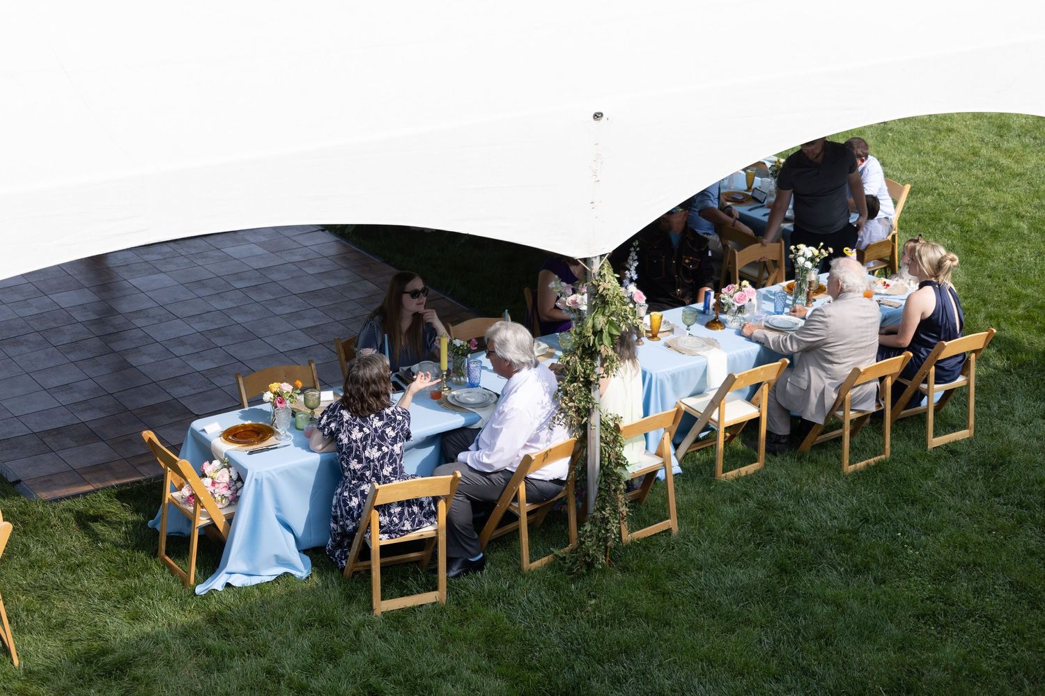 Outdoor wedding reception setup with wooden chairs and tables on grass lawn.