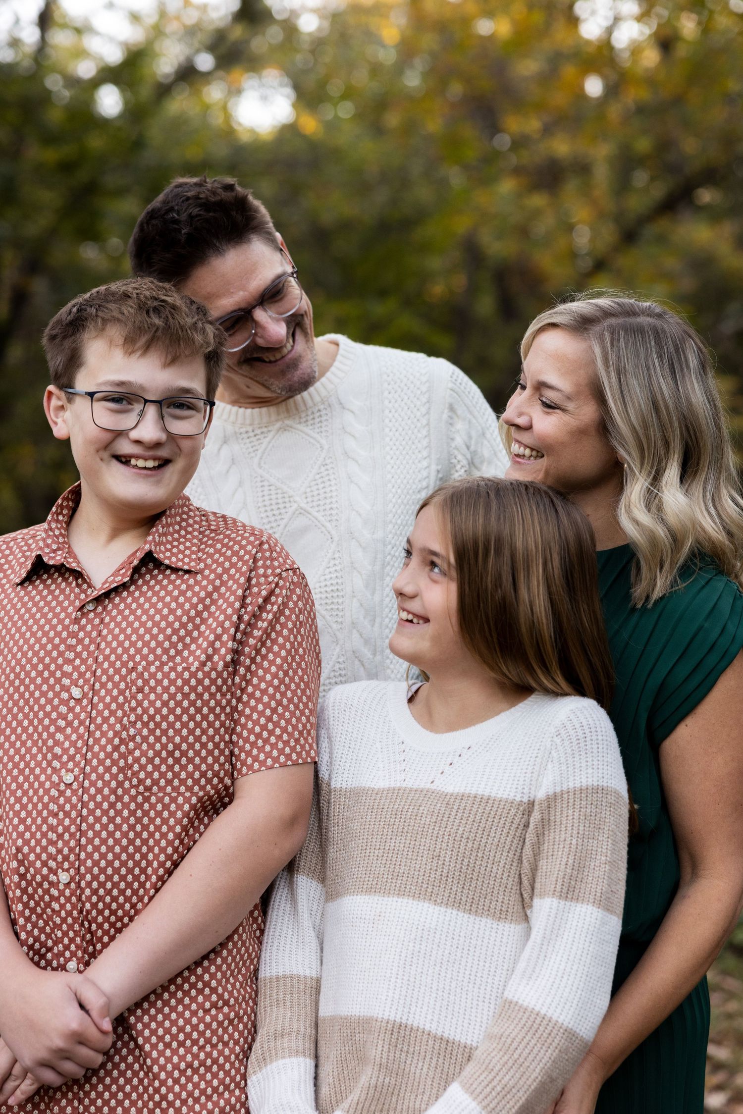 Family members share candid moments and laughter in an outdoor autumn setting.