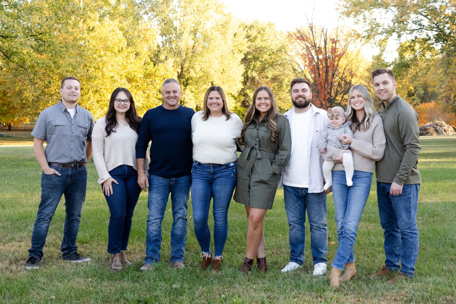 Extended family group poses together outdoors during fall season.