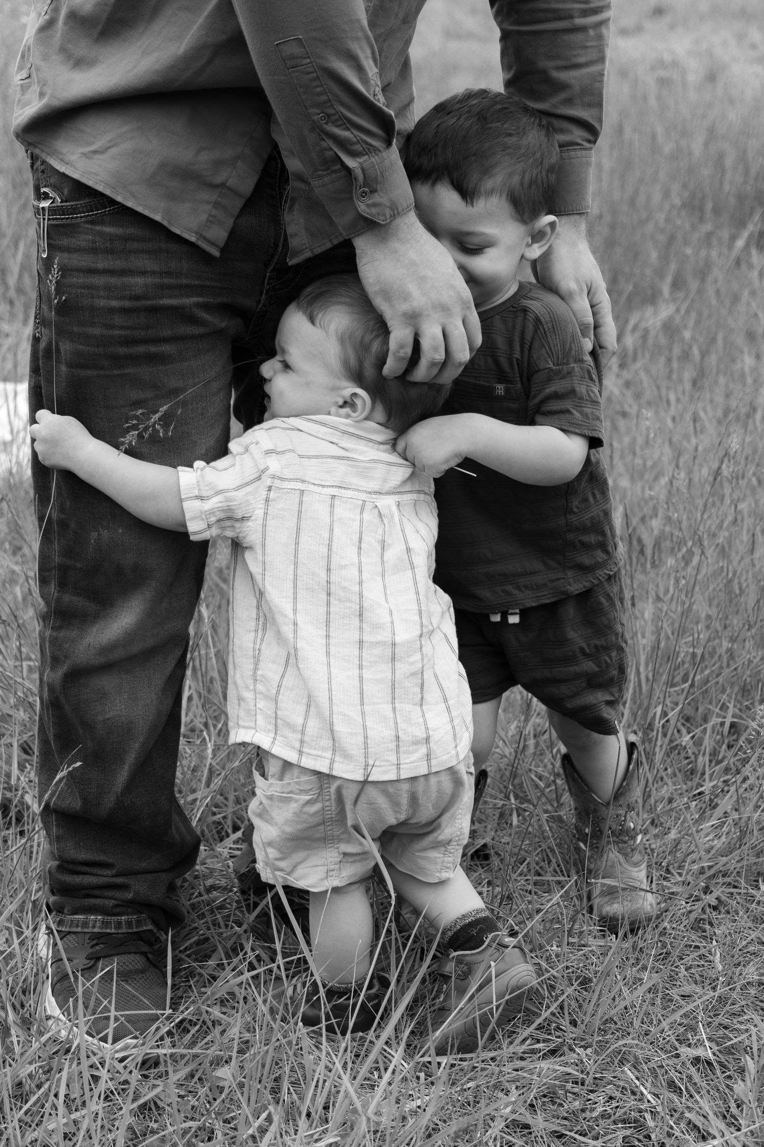 A black and white capture of family members embracing in a field.