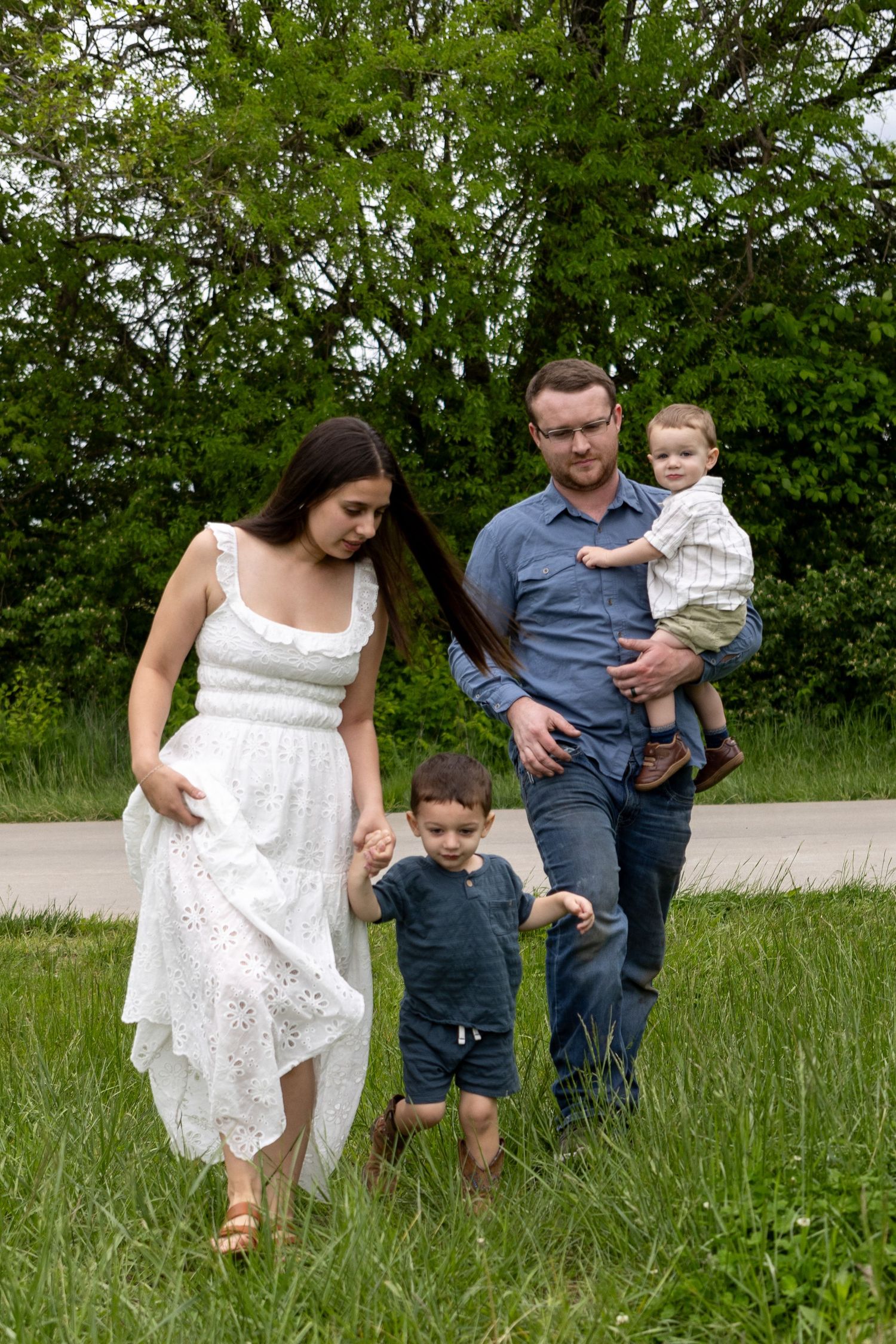A family walks together through a lush green field on a spring day.