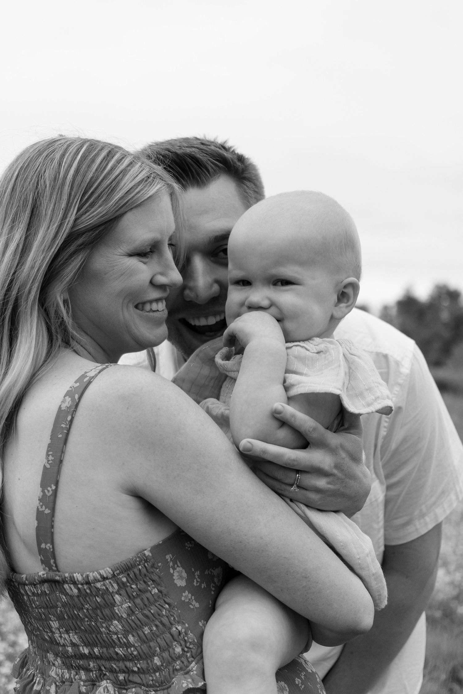 A joyful family moment captured in black and white showing parents cuddling with their baby in a series of candid shots.