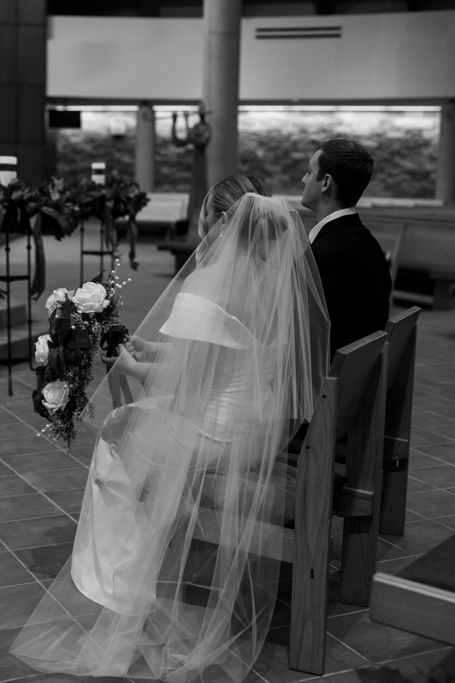 Black and white photos of wedding dress and veil details in elegant venue setting.
