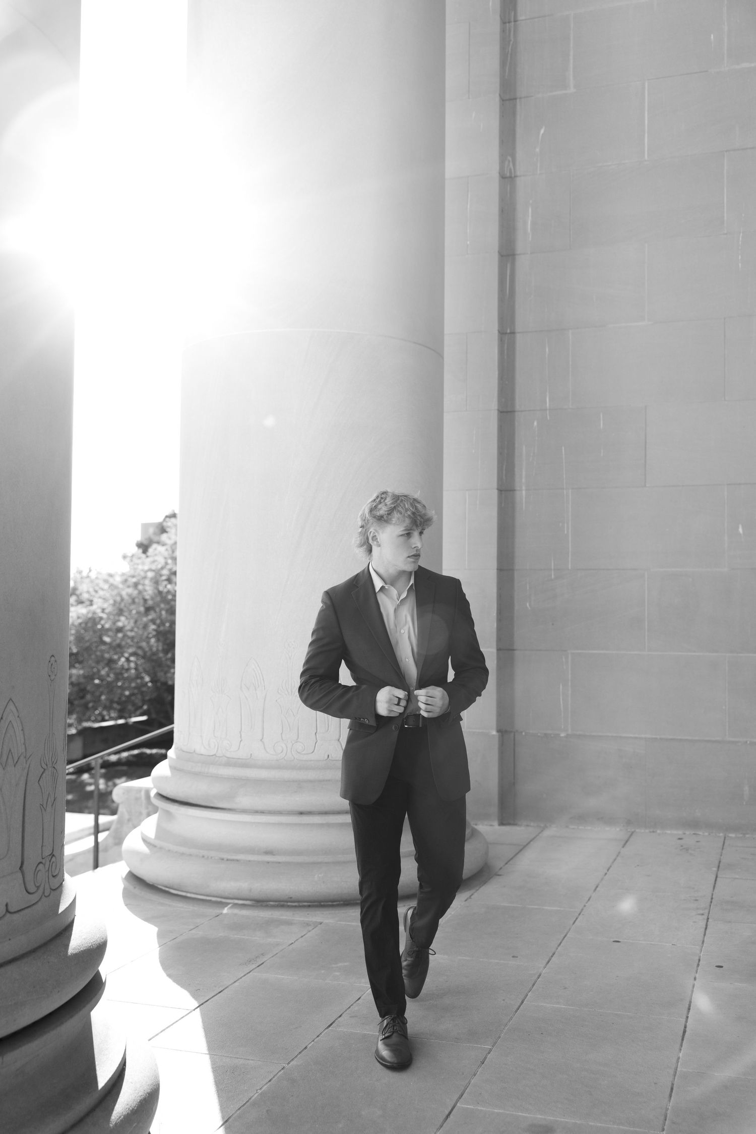A sequence of black and white photos showing a person in a suit walking past white columns in different poses.