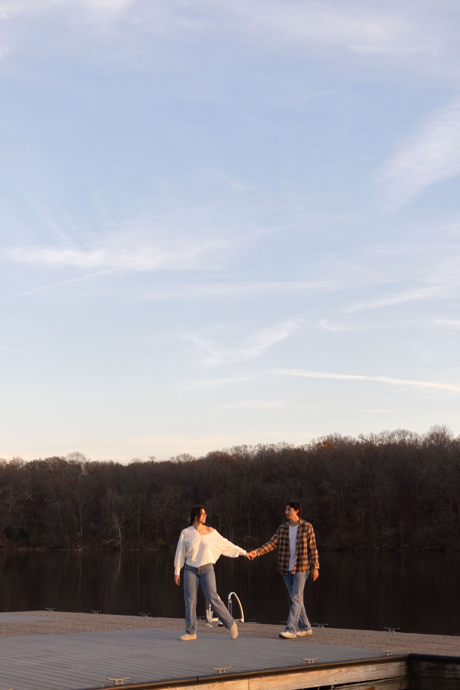Playful interactions between a couple on a lakeside dock at dusk.