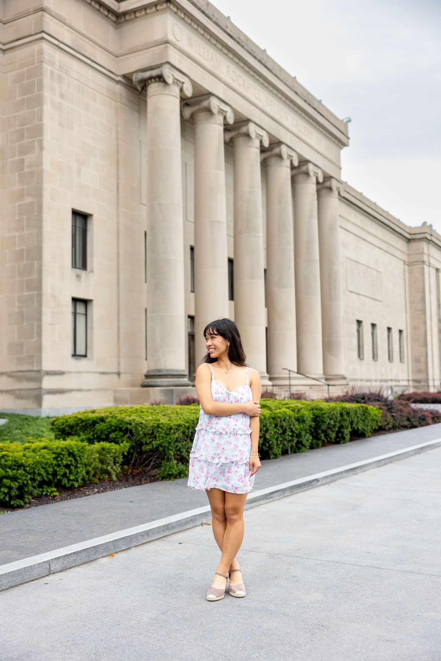 Classical stone building with columns serves as backdrop for outdoor photography session.