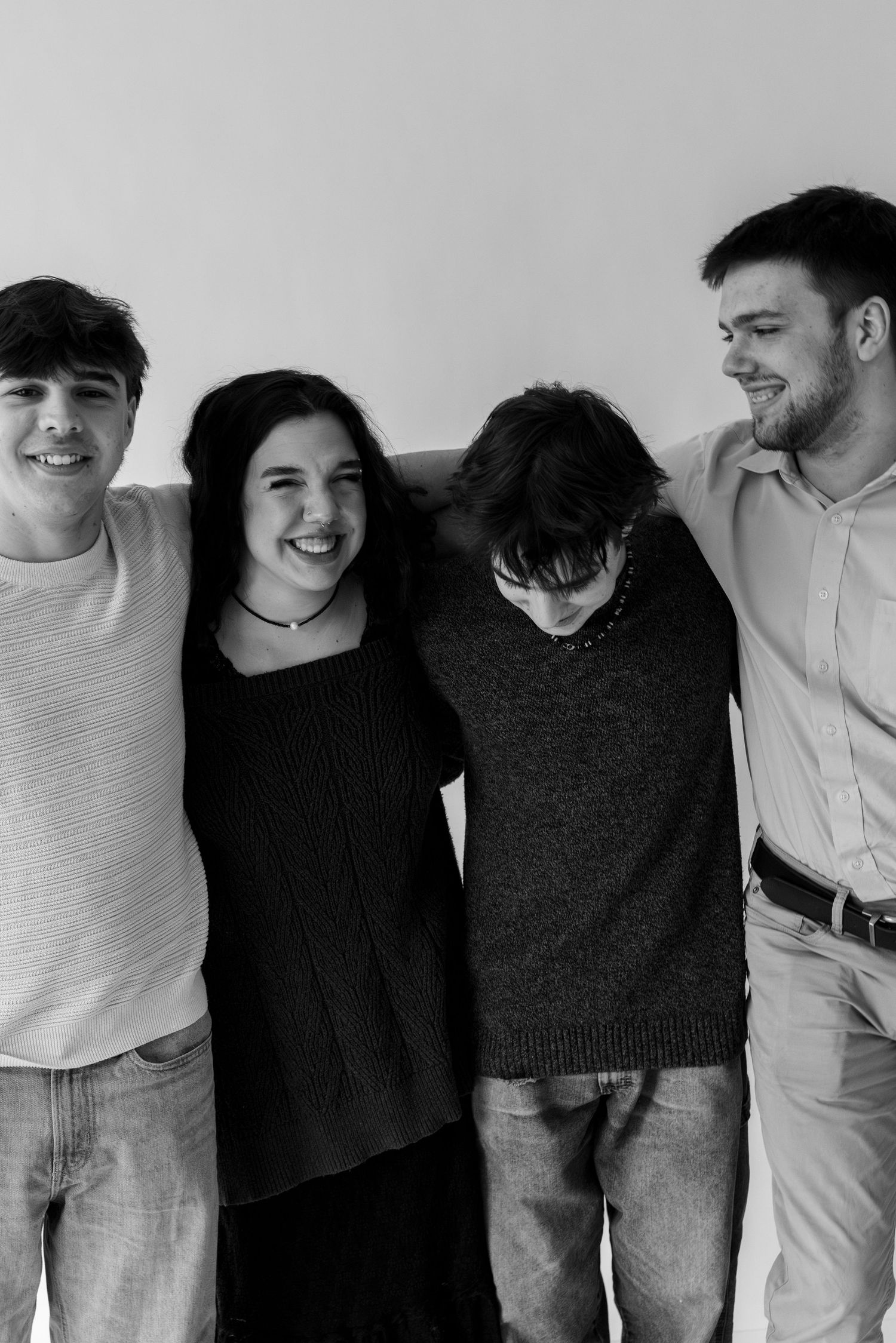 A group of people standing together in casual clothing against a white background in black and white.