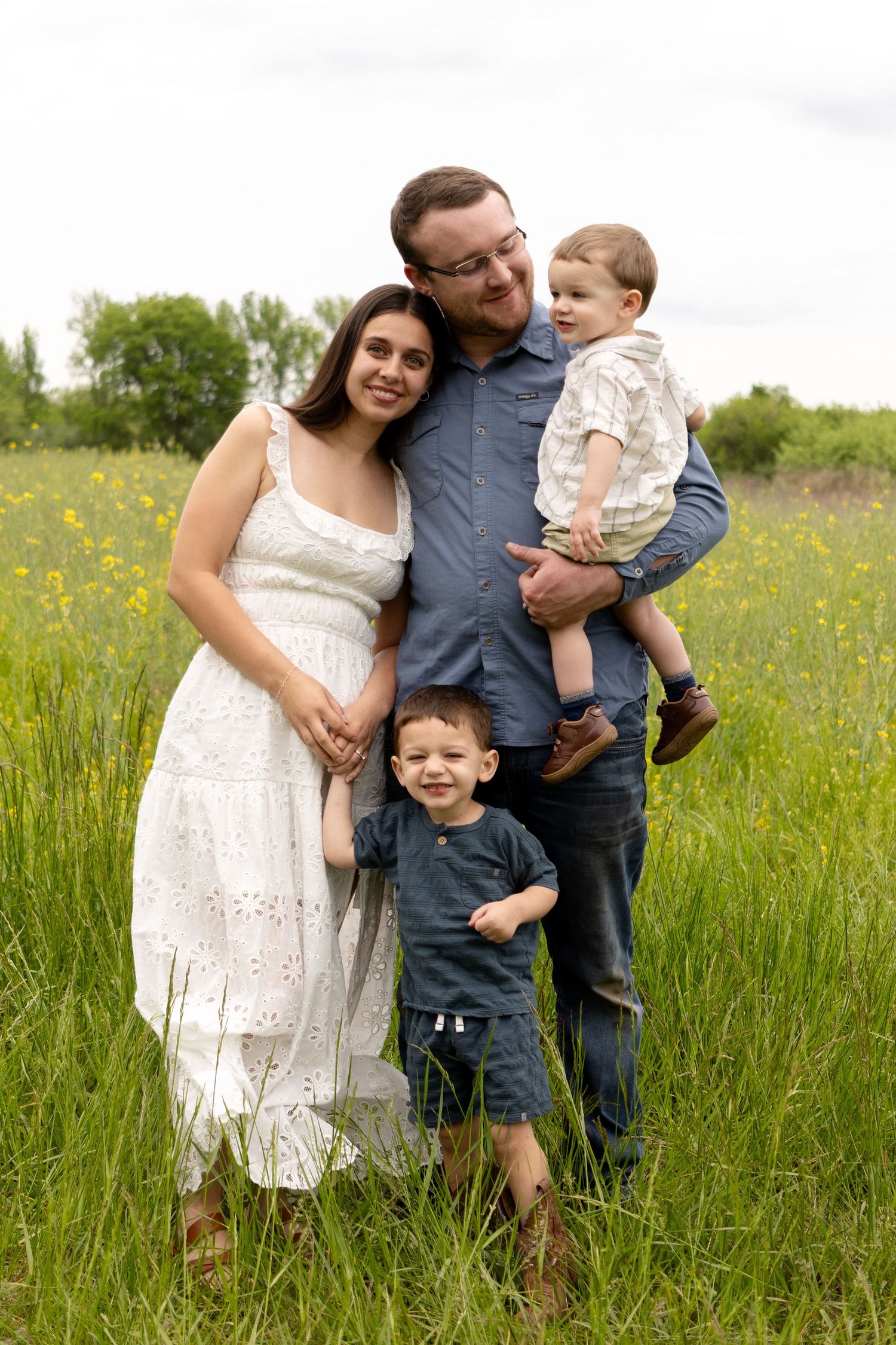 A family poses together in a wildflower meadow on a sunny day.