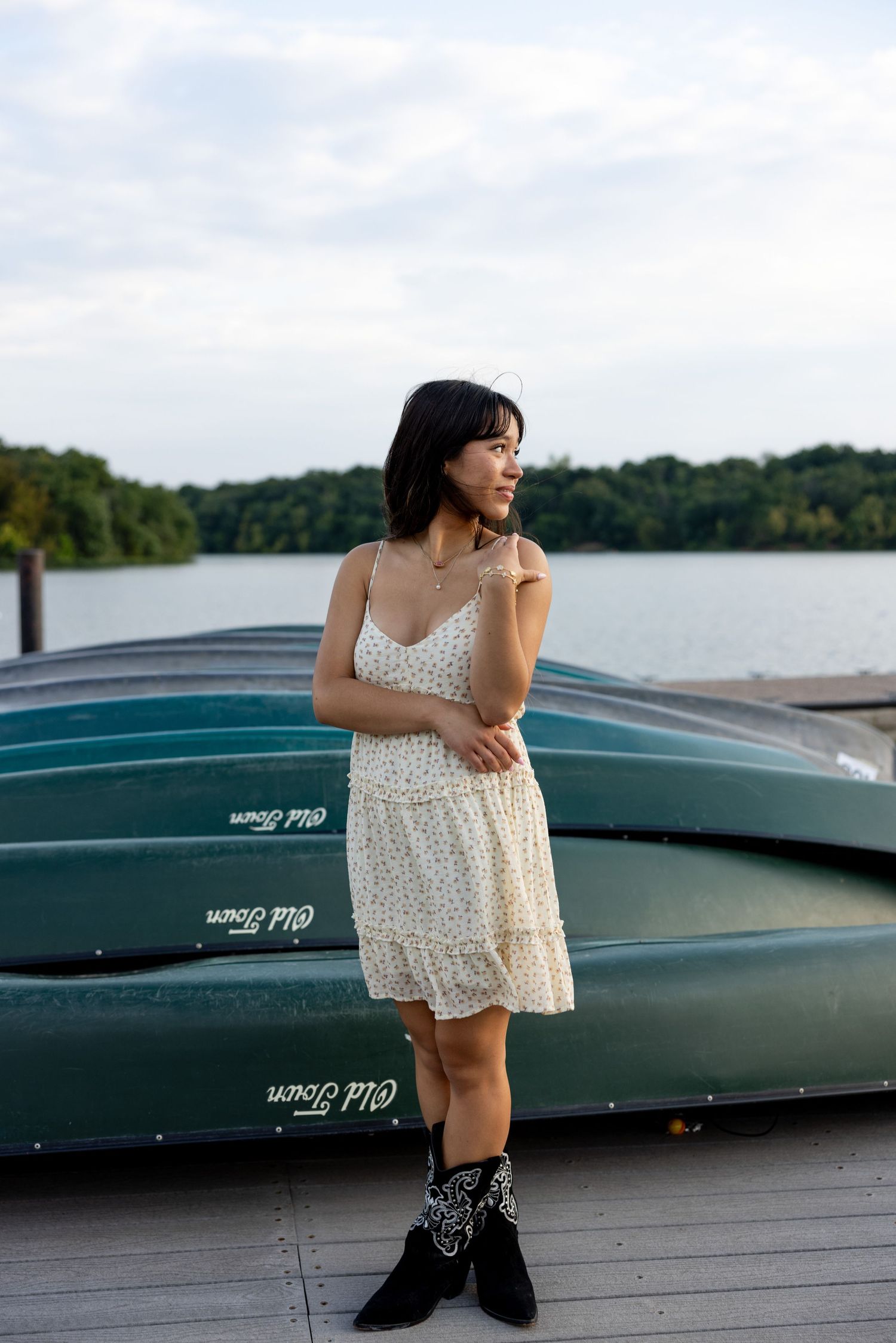 Senior posing in front of canoes at a lake in shawnee mission park