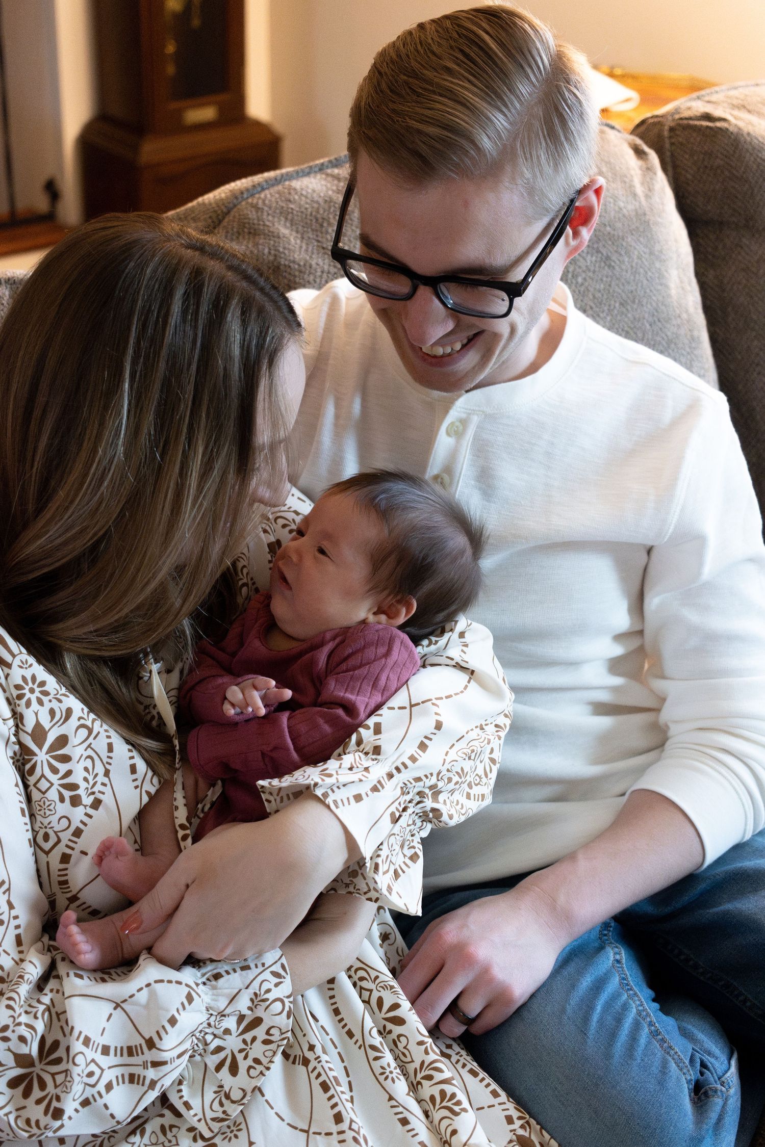 Family cuddles together on a couch in a tender moment.