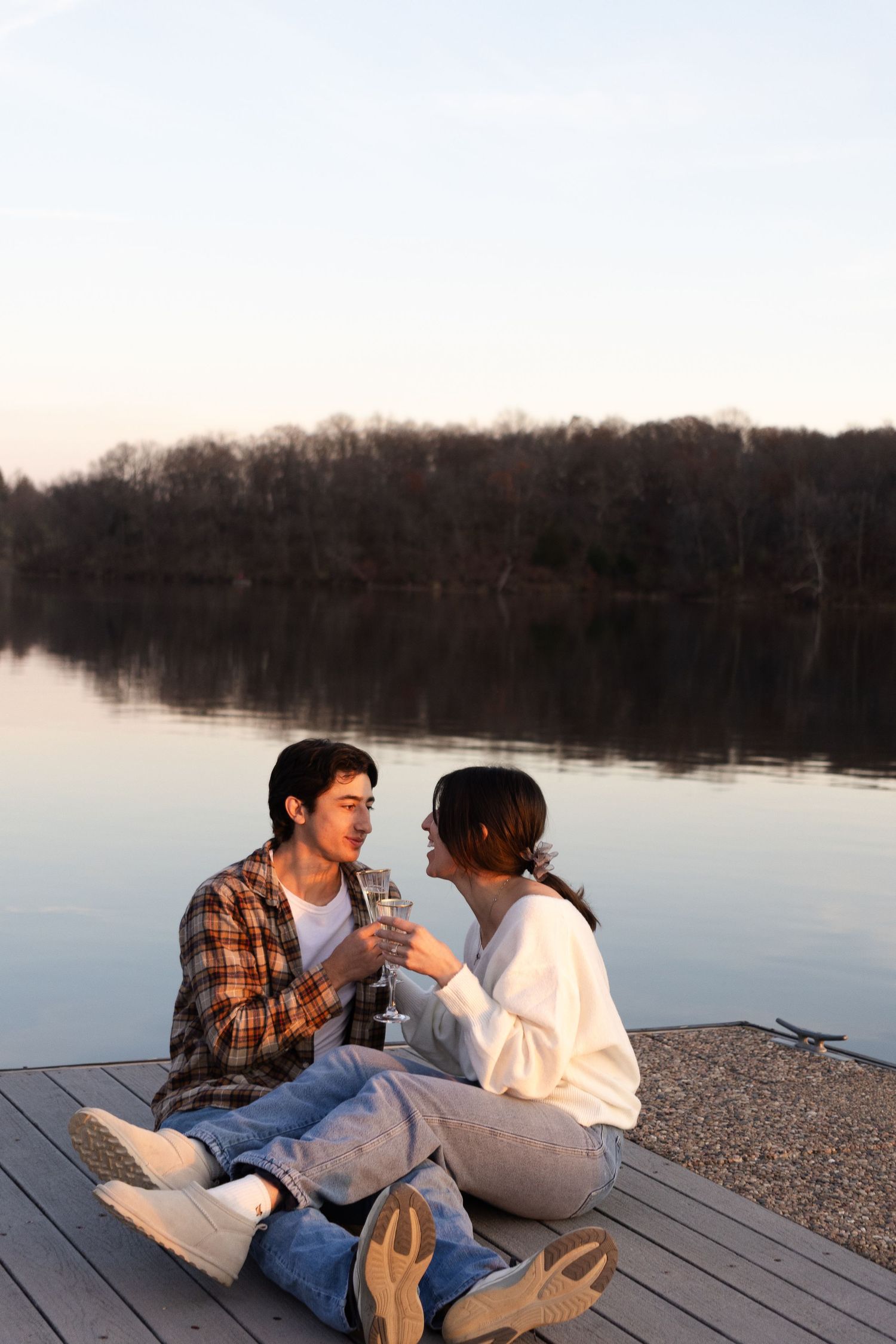 A couple relaxing together on a wooden dock overlooking a serene lake.