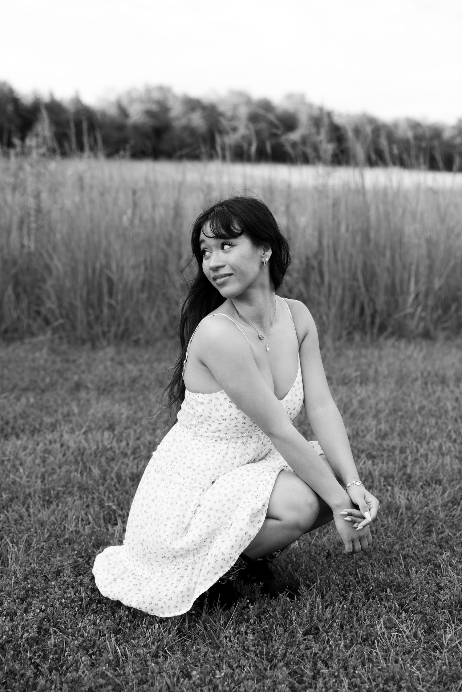 Senior posing for photo sitting in field