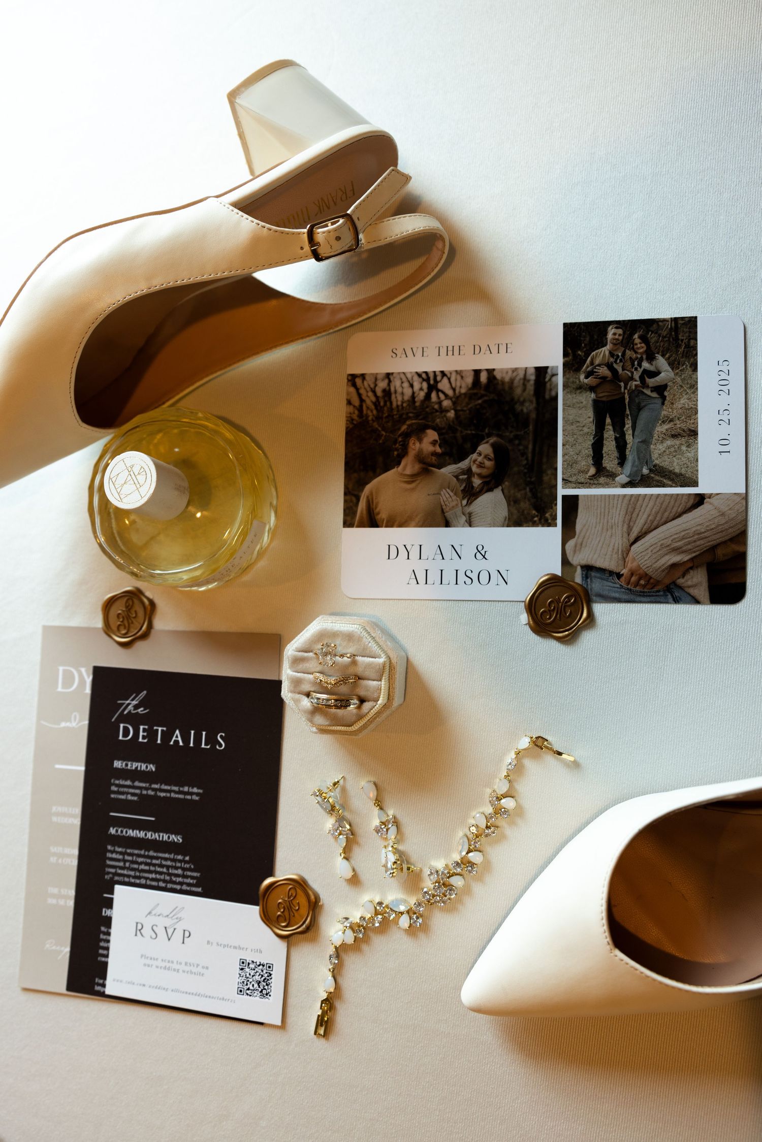 Wedding invitation suite with black and white cards, jewelry accessories, and champagne bottles arranged on white surface.