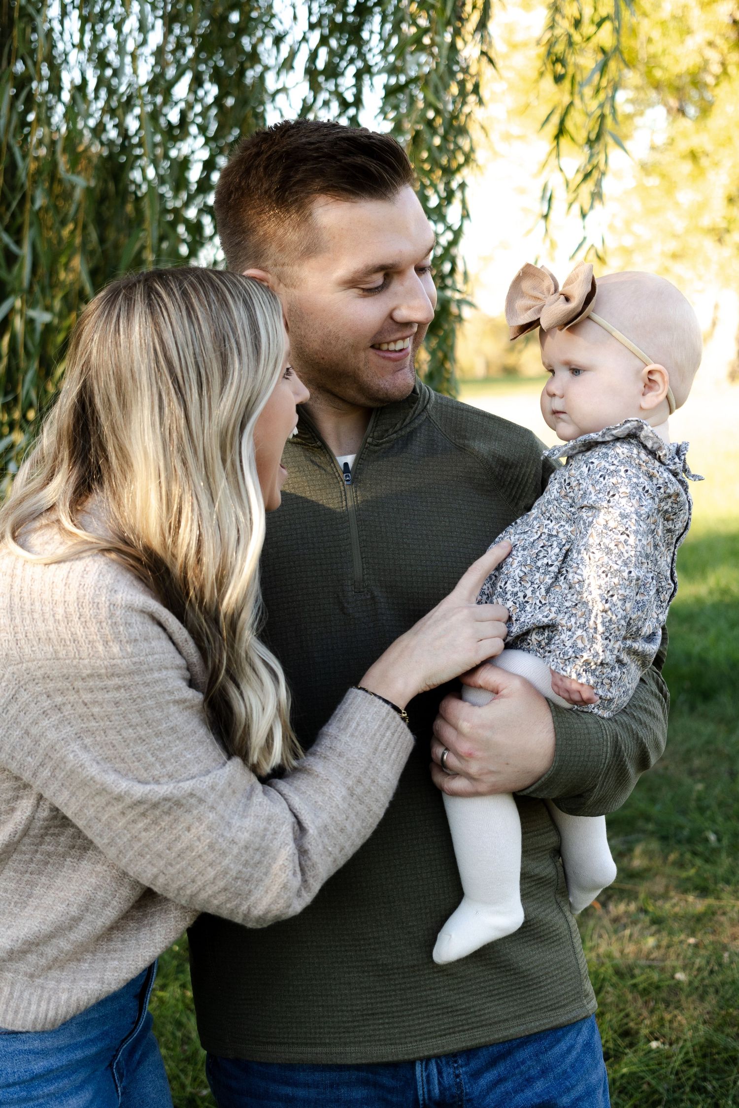 Family shares playful outdoor moments during autumn with golden sunlight filtering through trees.