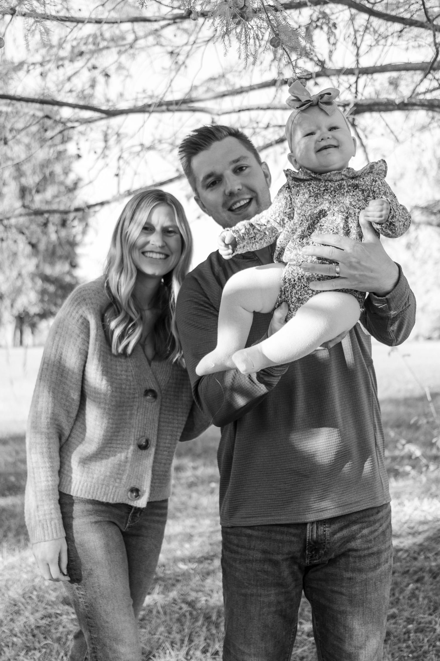 Black and white family portrait captured outdoors with natural expressions.