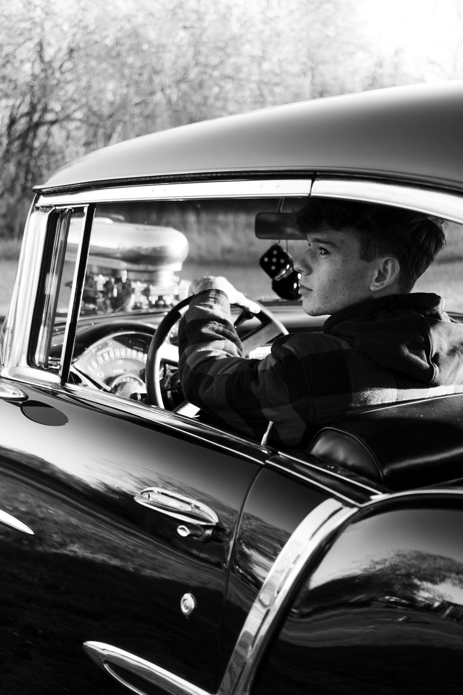 Black and white profile shot through vintage car window.