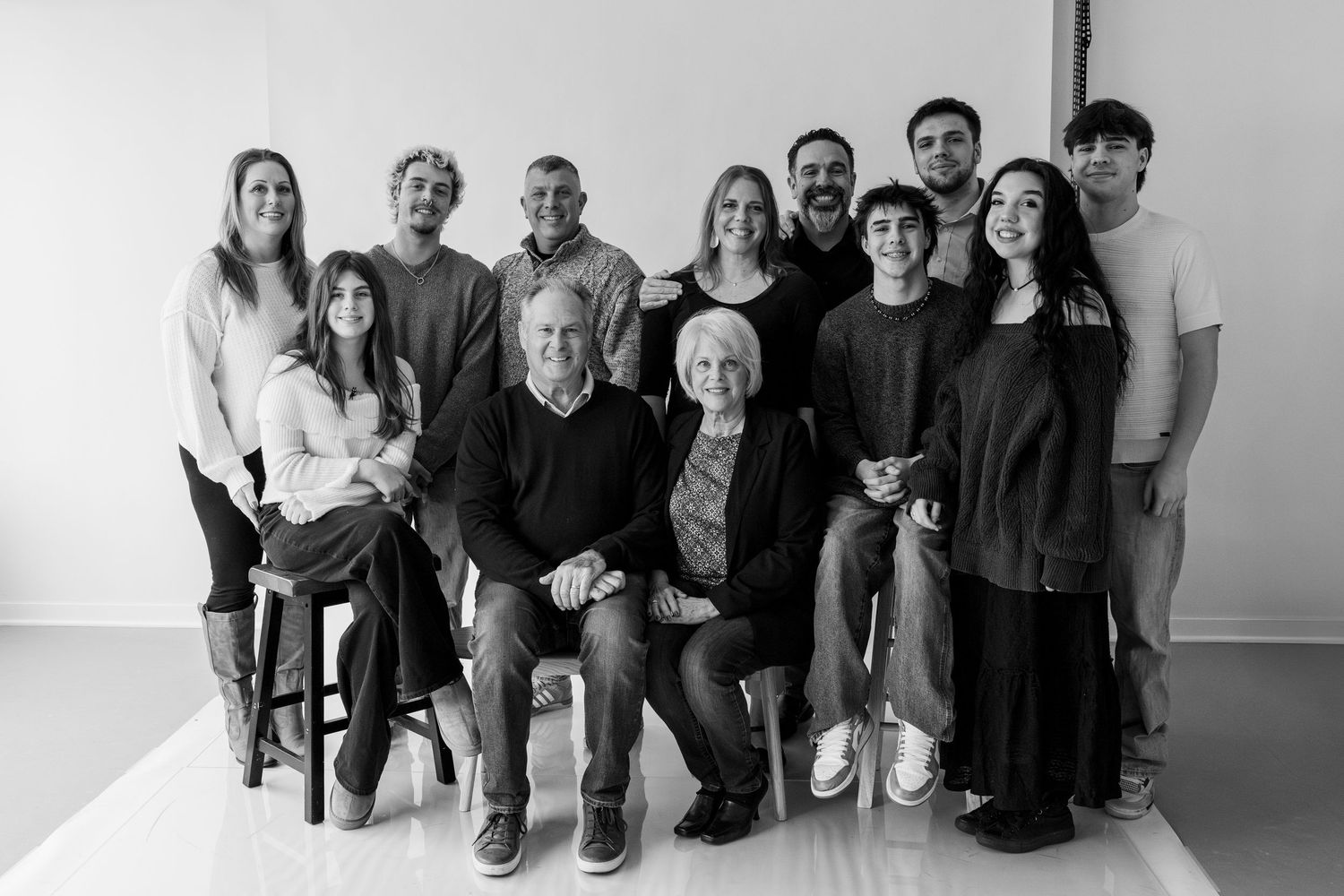 A group poses together in a minimalist studio setting against a white background.