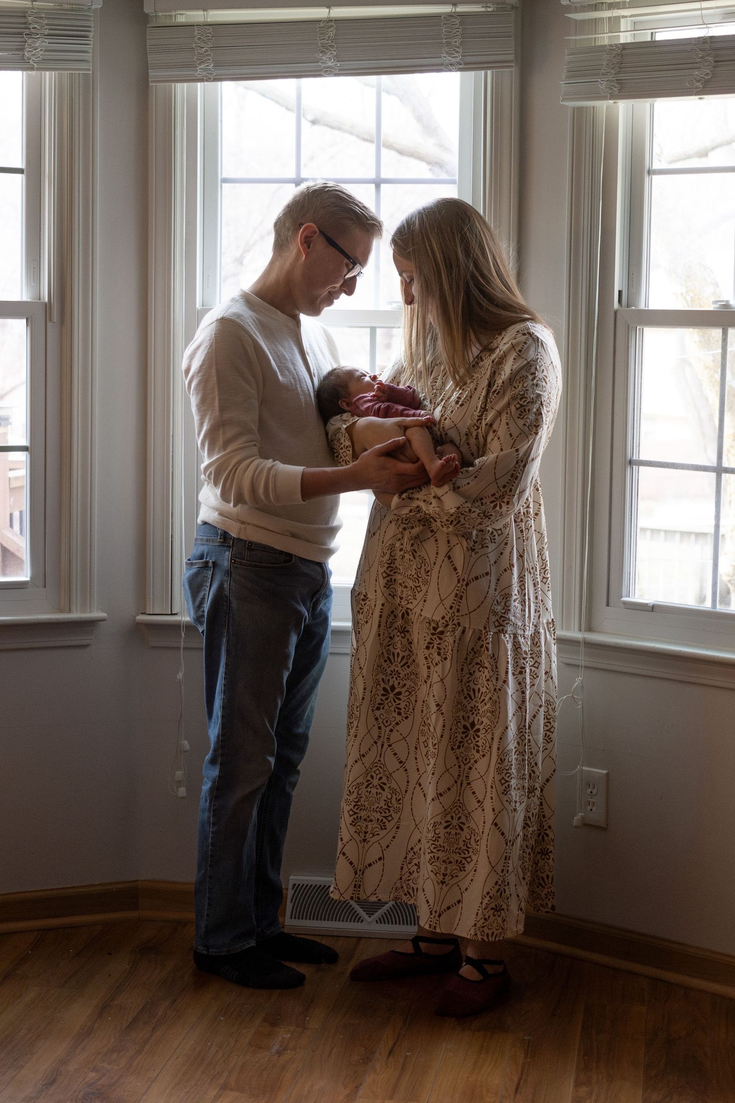 A couple shares an intimate dance moment in a sunlit room with hardwood floors.