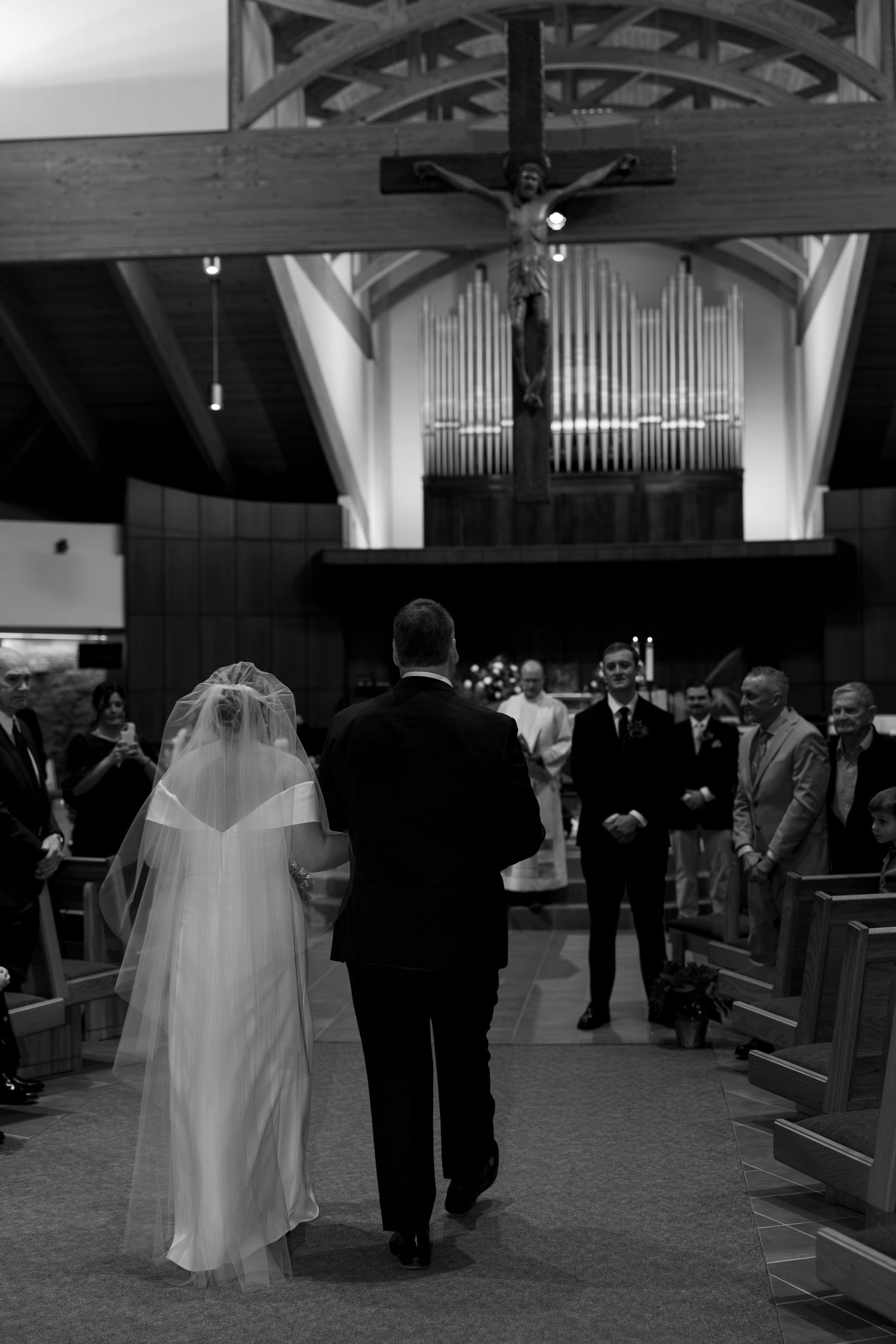 A black and white photo of a wedding ceremony in a church with organ pipes visible.