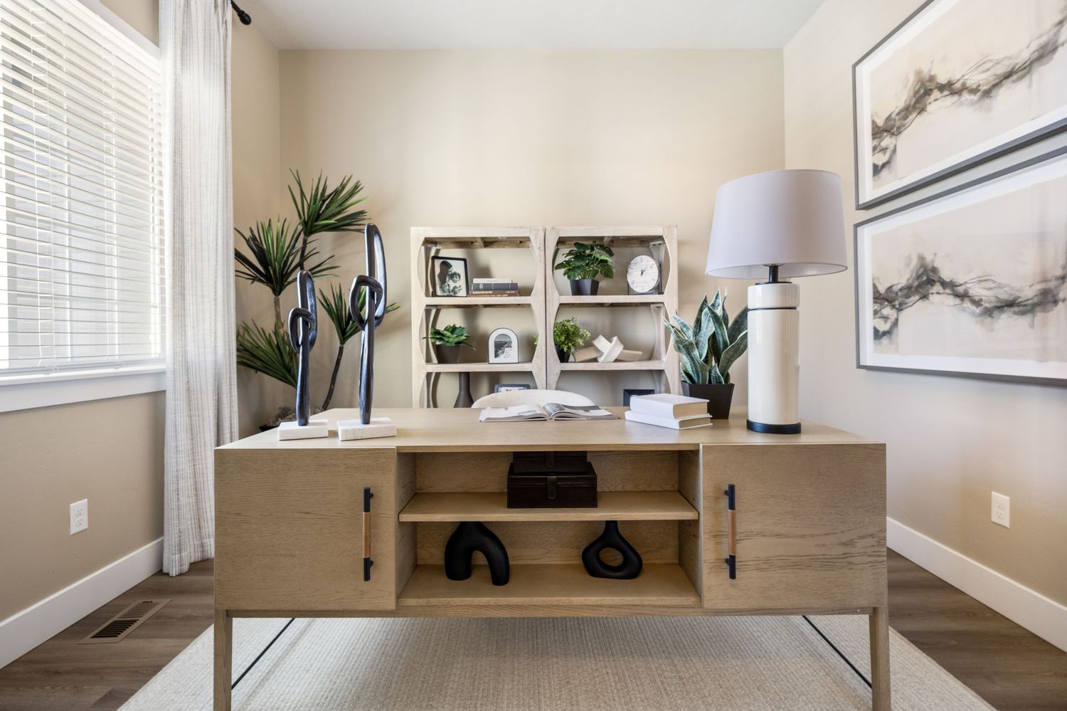 Minimalist home office space with light wood desk, white walls, and window blinds creating a bright, airy workspace.