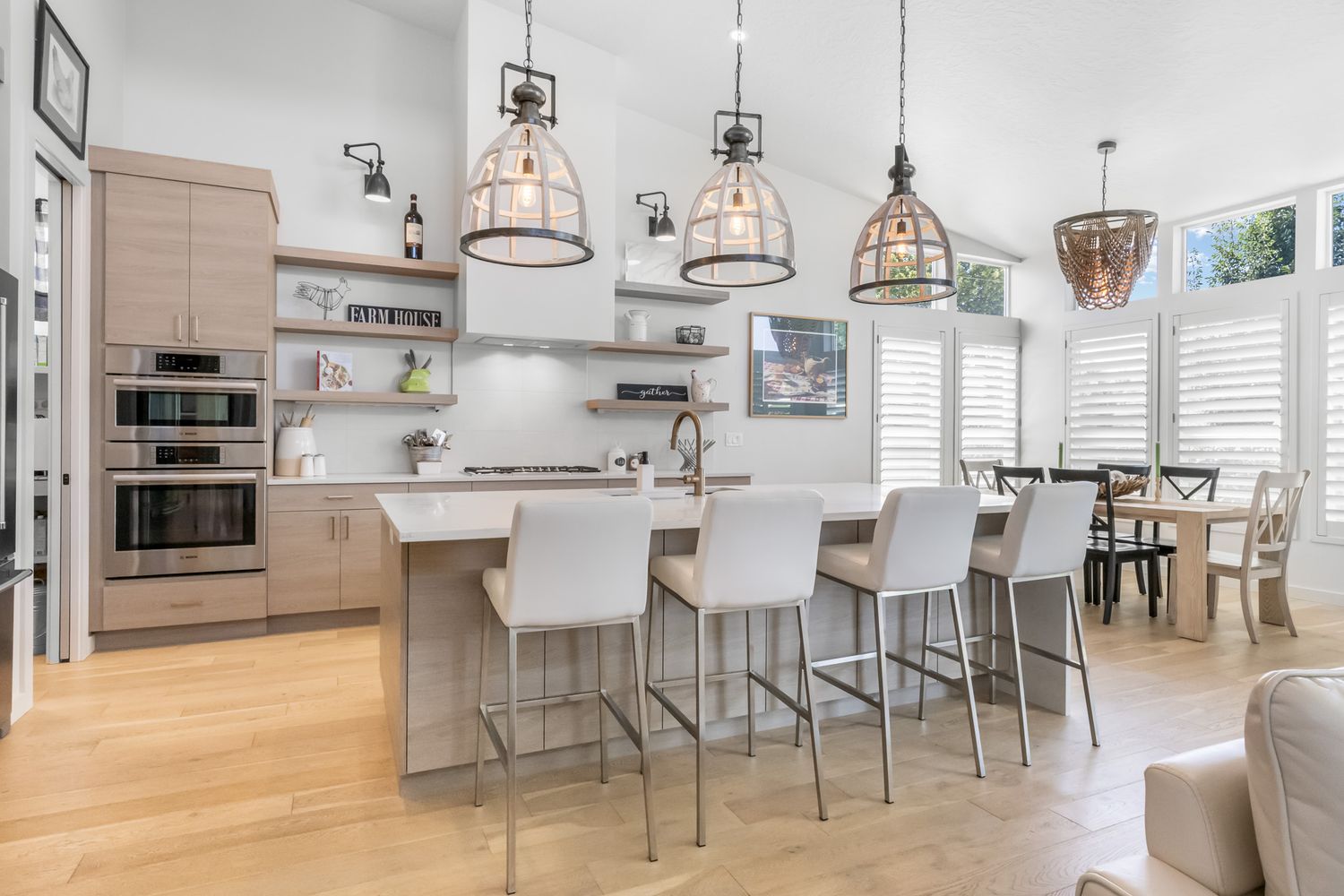 Bright modern open concept living area with white walls, wood flooring, and contemporary pendant lighting fixtures.