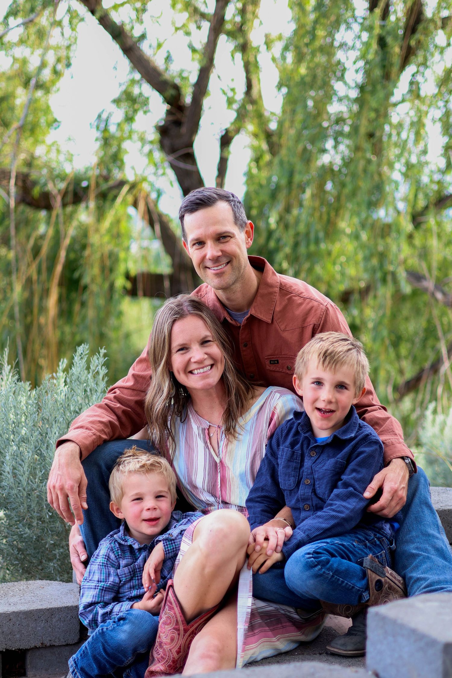 Family group photo on stone steps with willow tree and sage brush landscaping.