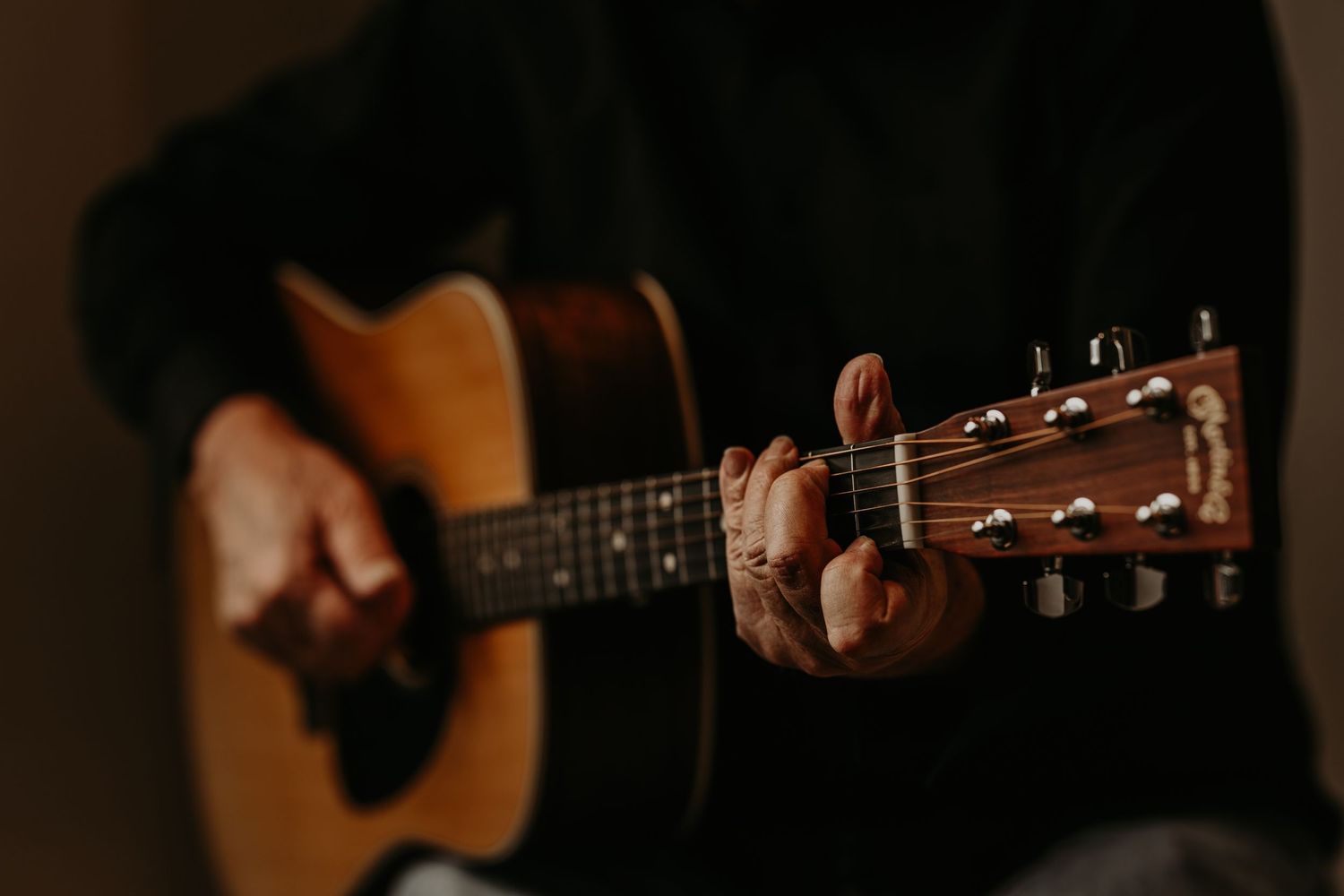 Close-up shots of hands playing acoustic guitar strings and fretboard in warm lighting.