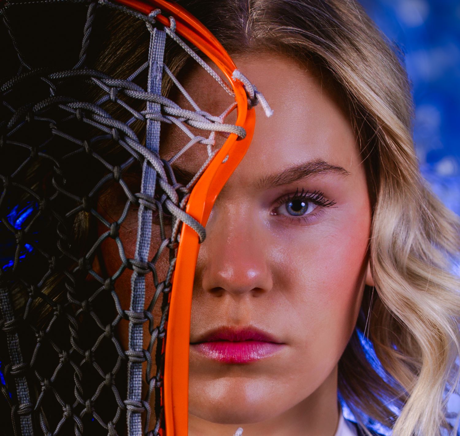 Close up portrait with orange headphones against blue background and dramatic lighting effect.