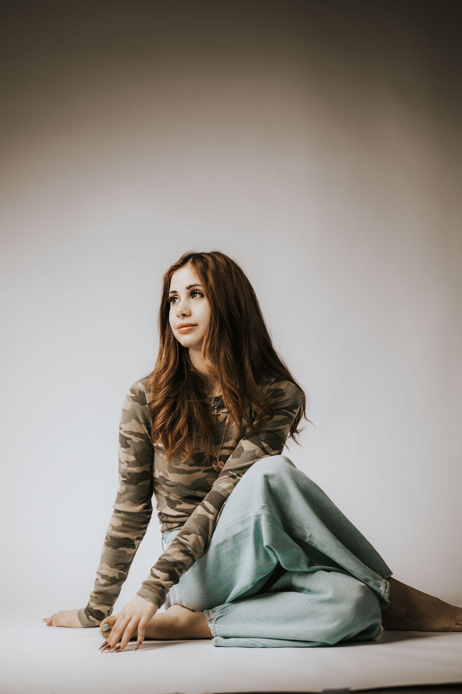 A sequence of artistic portrait photos showing a person in a camouflage top and light blue skirt laying on a white surface.