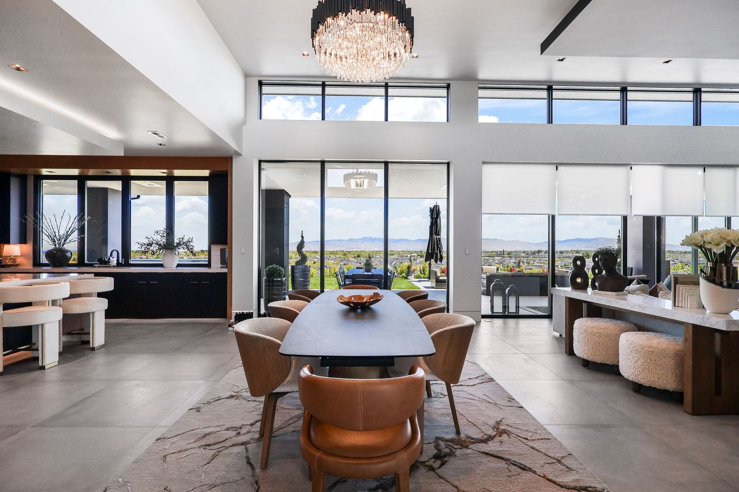 Luxurious open-plan living area with high ceilings, crystal chandelier and panoramic windows overlooking city views.