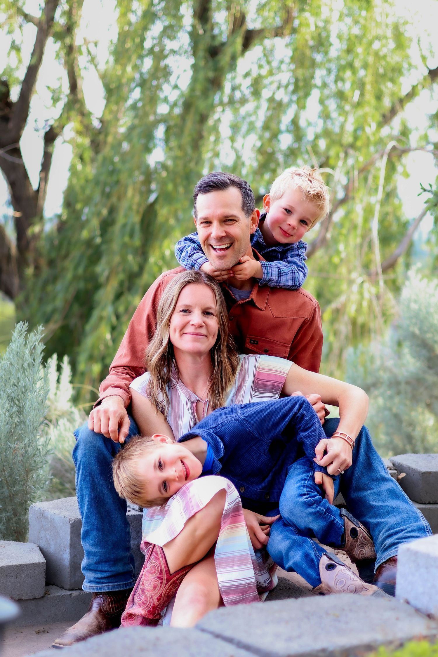 Playful family portrait with everyone laughing together on outdoor steps.