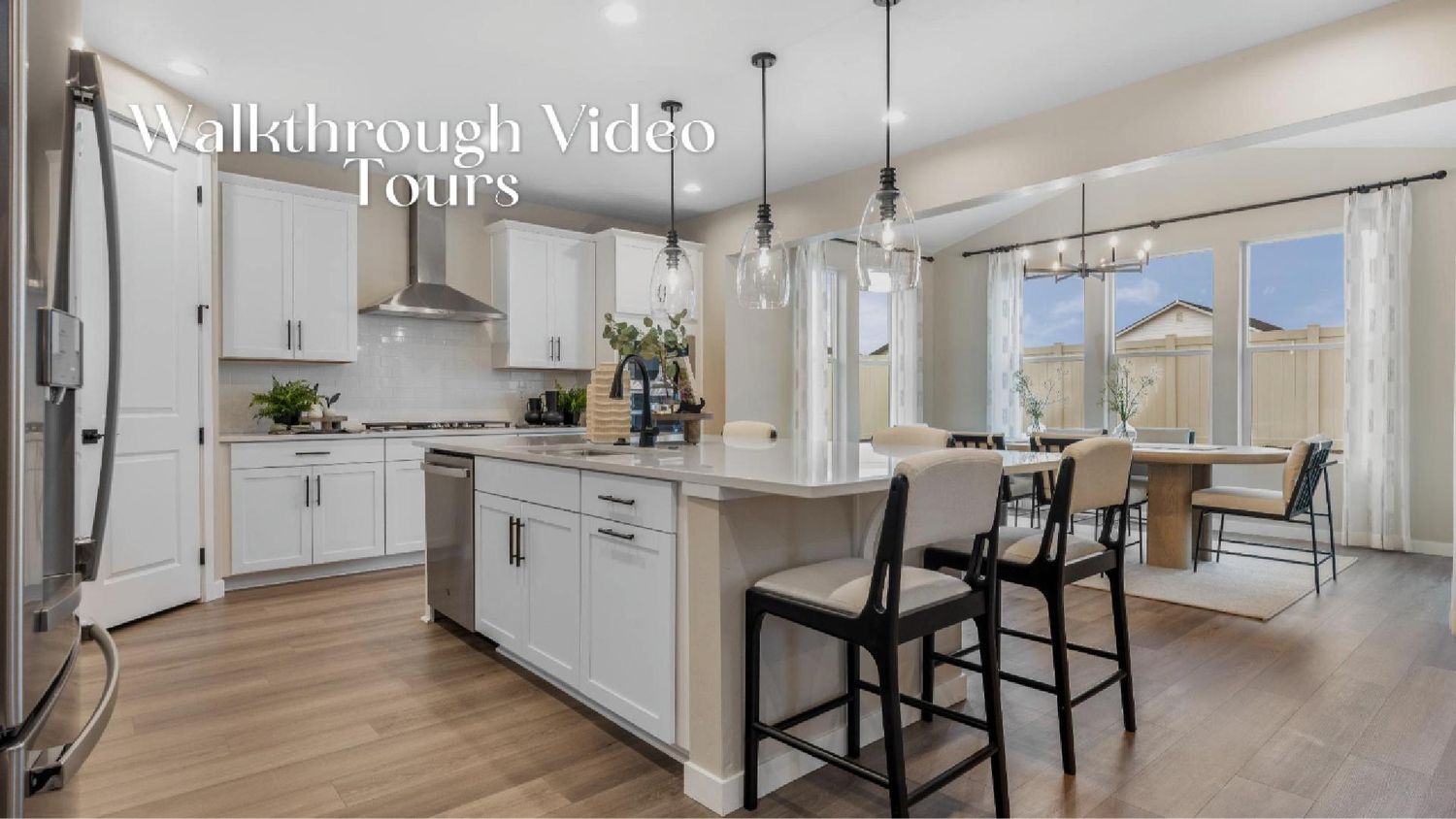 Modern white kitchen and living room with hardwood floors and open concept layout showcases sleek design and natural light.